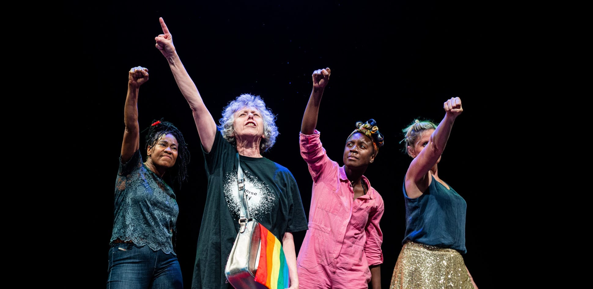 Actors on stage with fists raised in the air