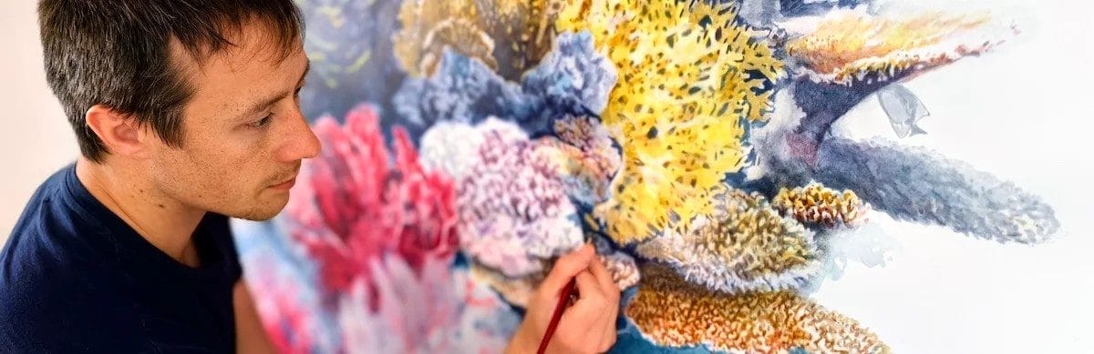 A male artist drawing a colourful ocean reef