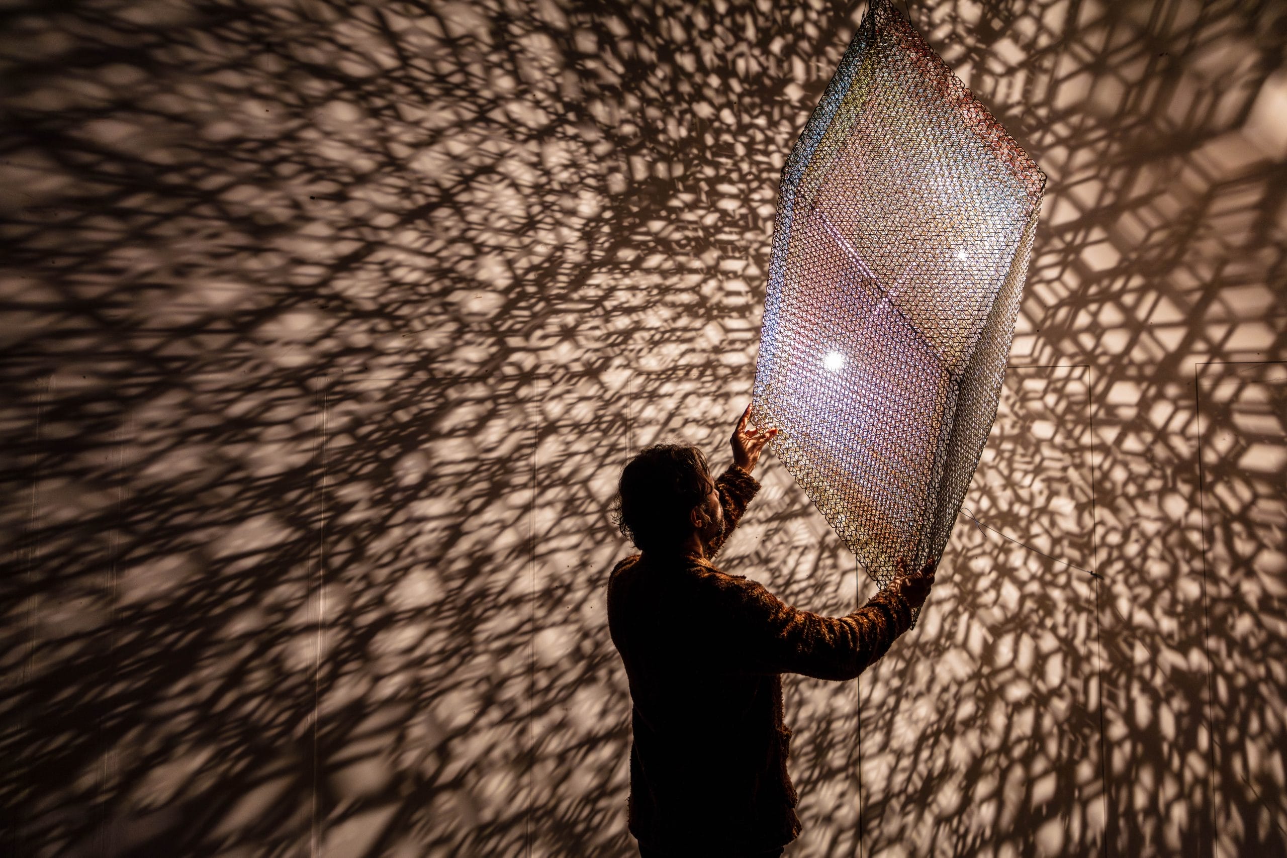 A silhouette of a man, surrounded by dappled light.