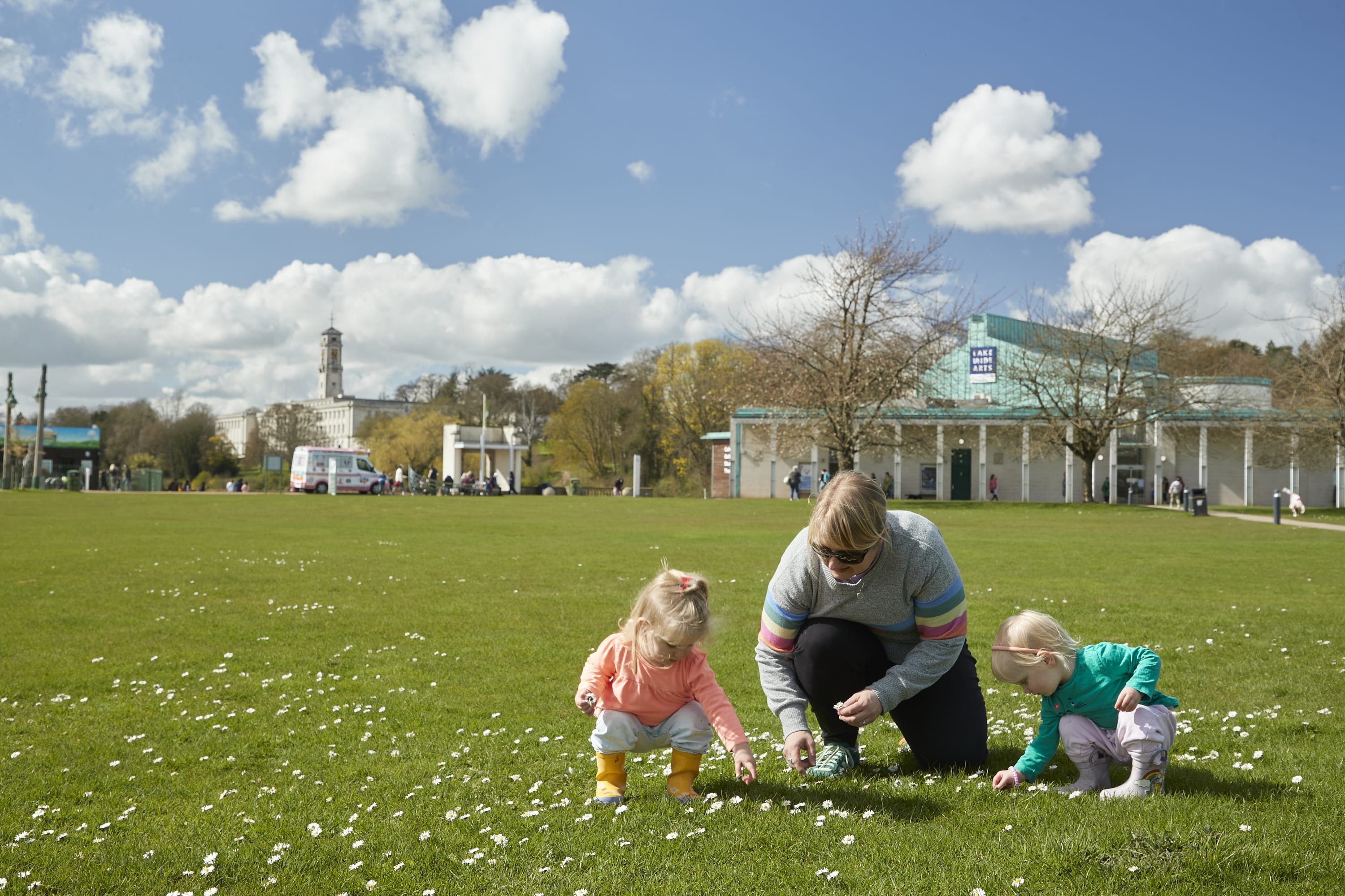 A young family play on the grass outside the DH Lawrence Pavilion