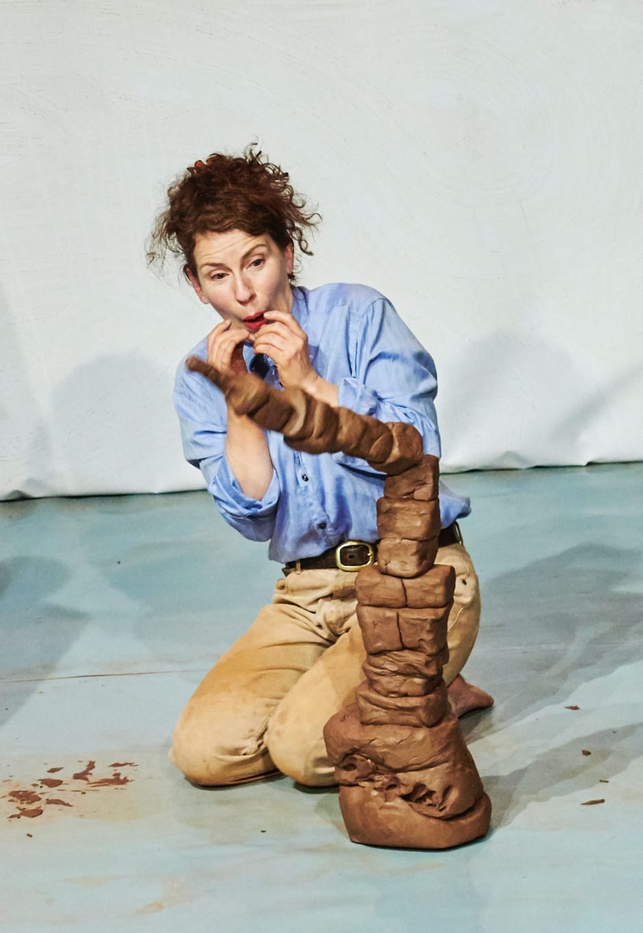 a woman watches as a tower made of clay is about to fall down