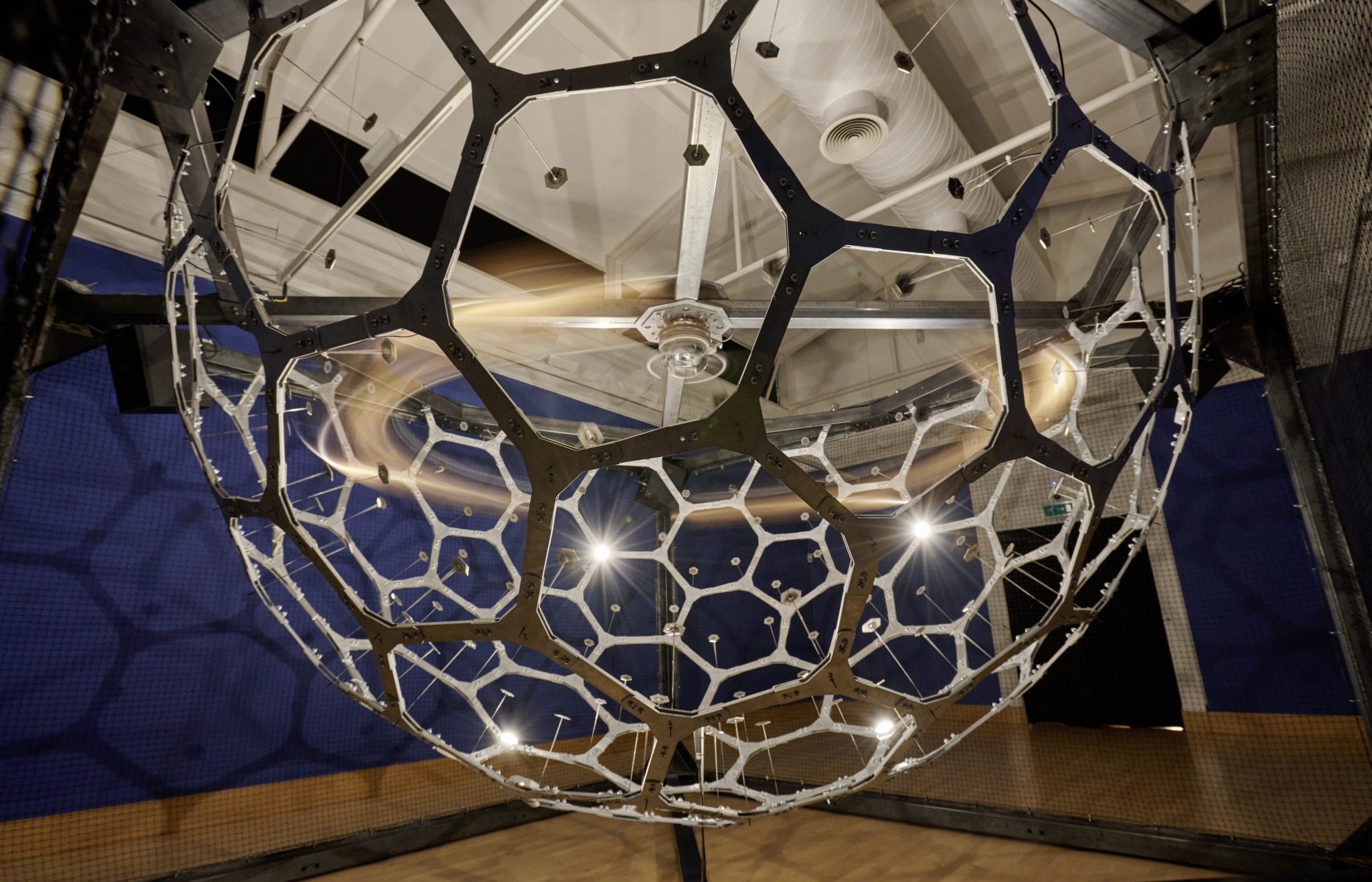 A spherical metal cage, containing moving bells.