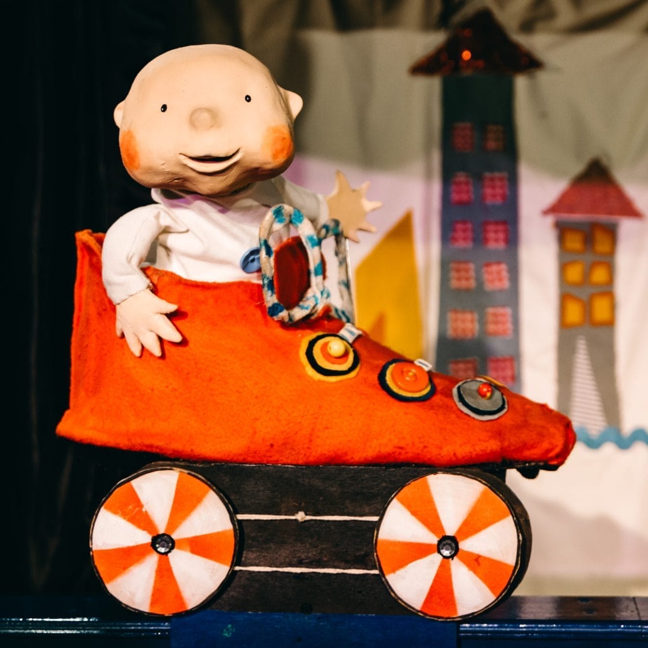 A puppet of a baby sits in a red roller skate.