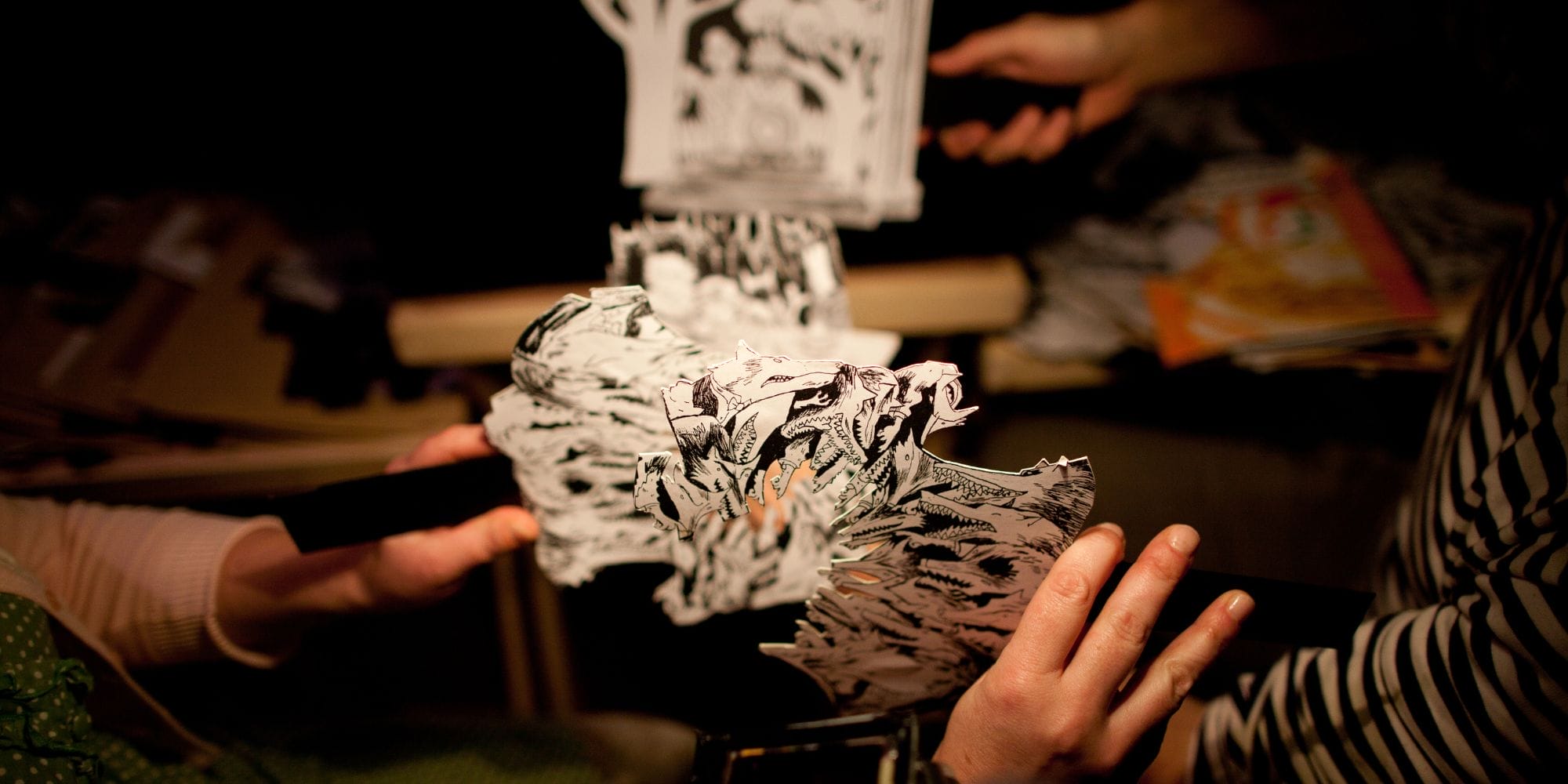 some hands holding paper cut-outs of wolfs