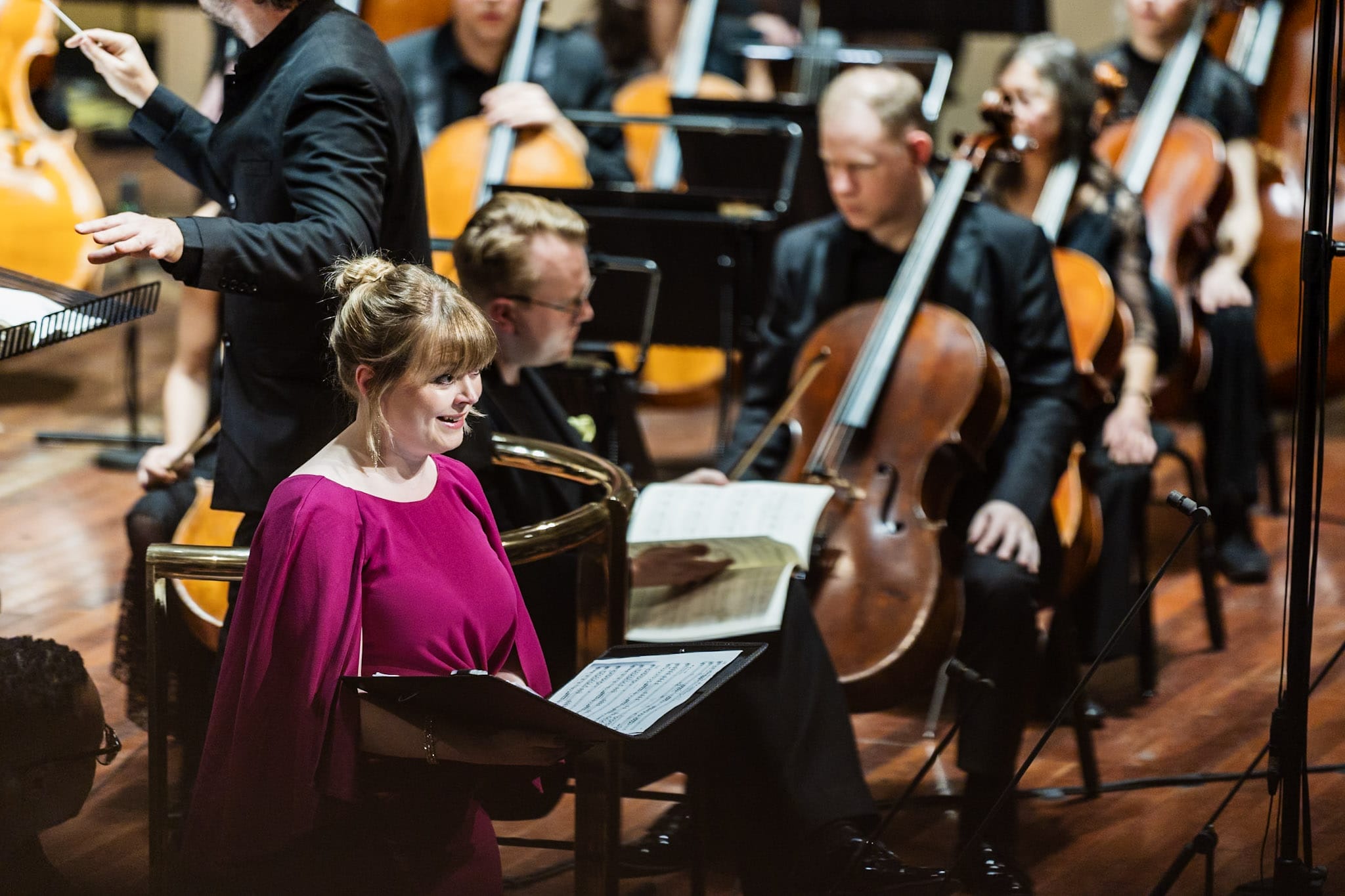 a woman sings on stage with the orchestra visible in the background