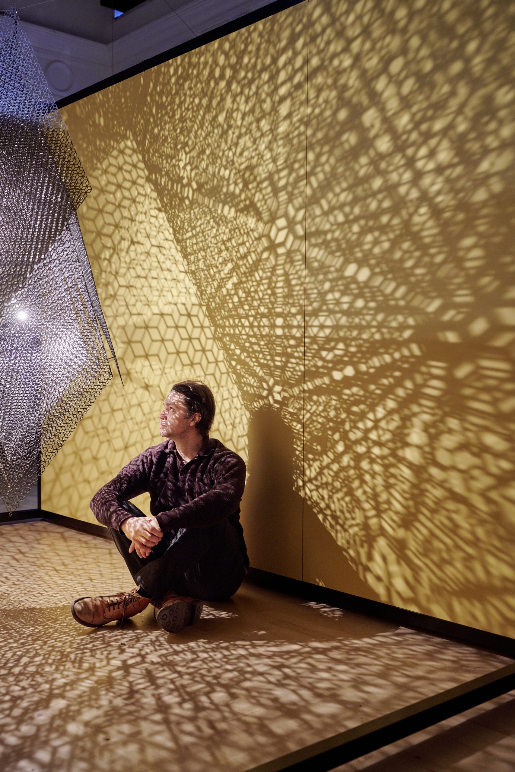 Artist Conrad Shawcross sits in the light pattern given off by his latest art installation