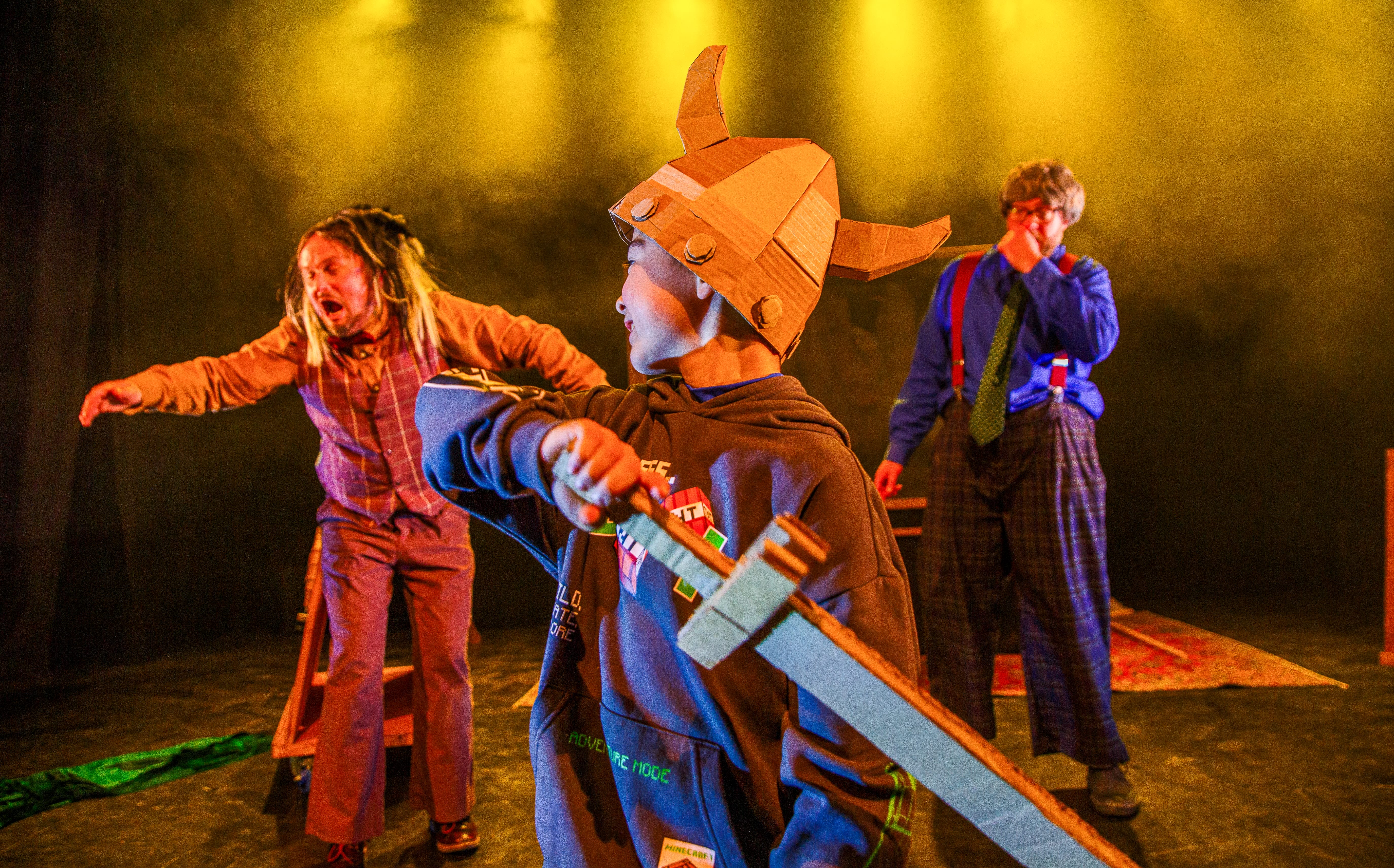 A boy wearing a cardboard Viking hat, holds a cardboard sword.