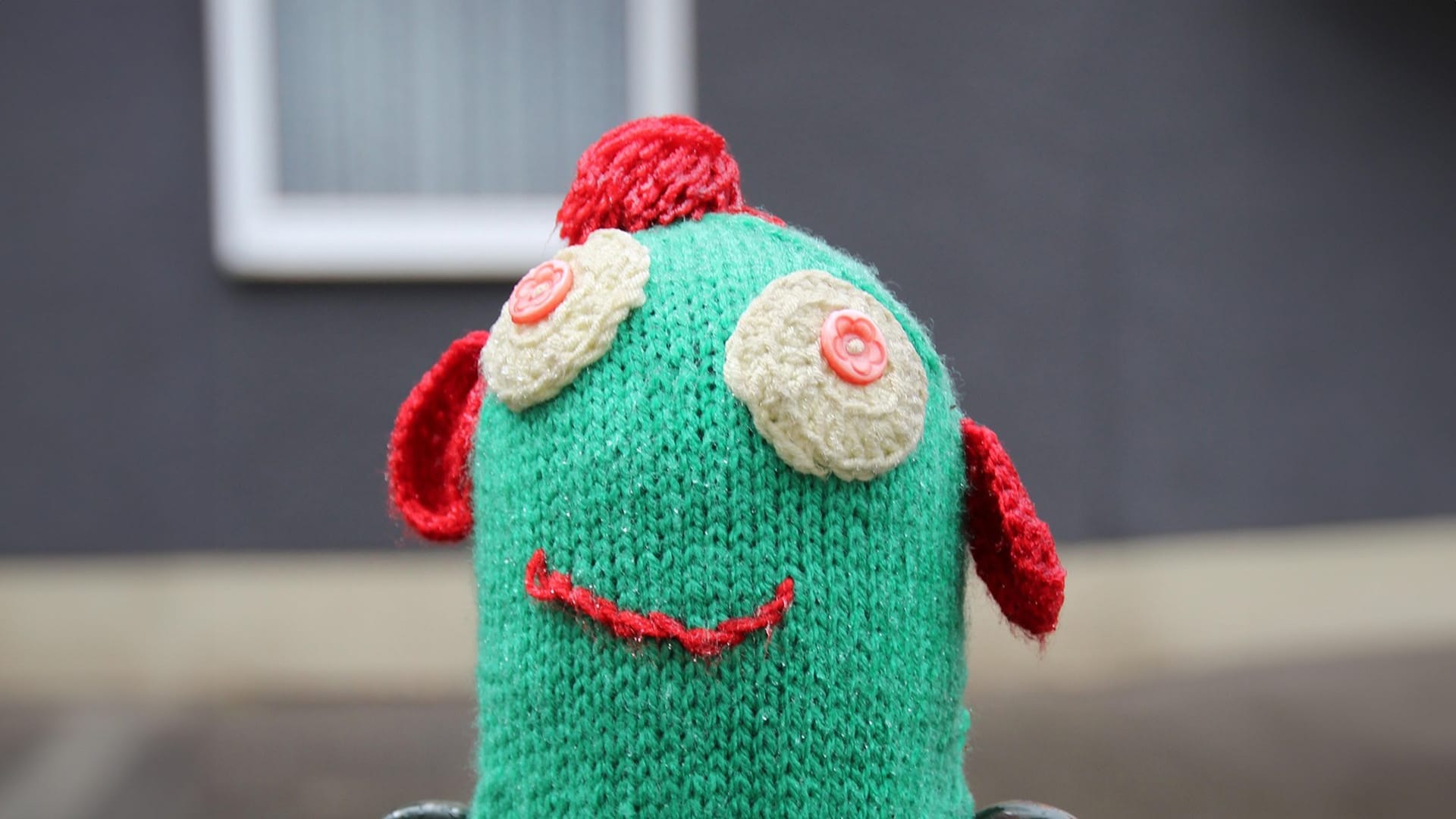A green sock puppet with red ears and a smiley face