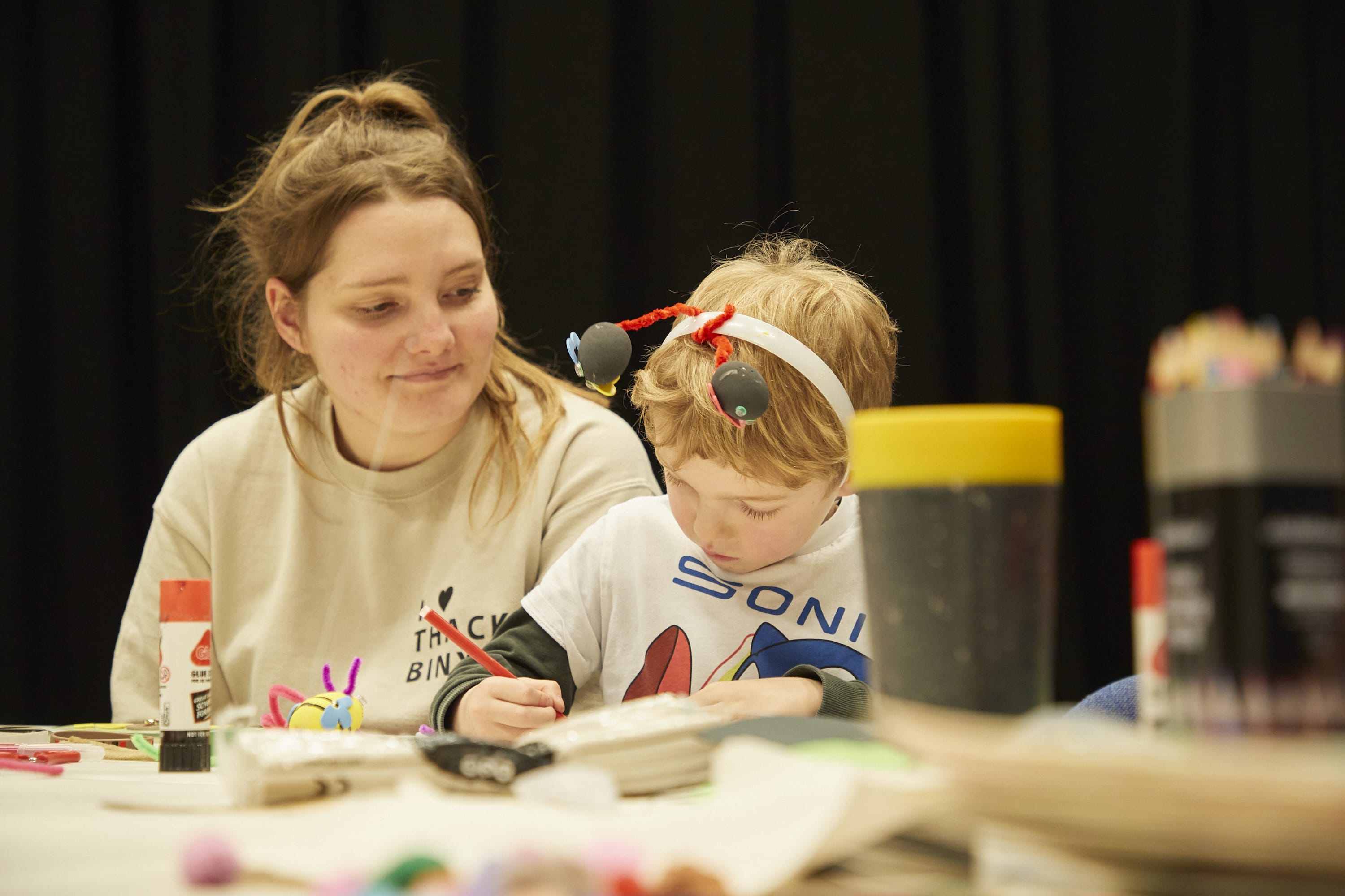 A woman and child sit at a table undertaking craft activities.