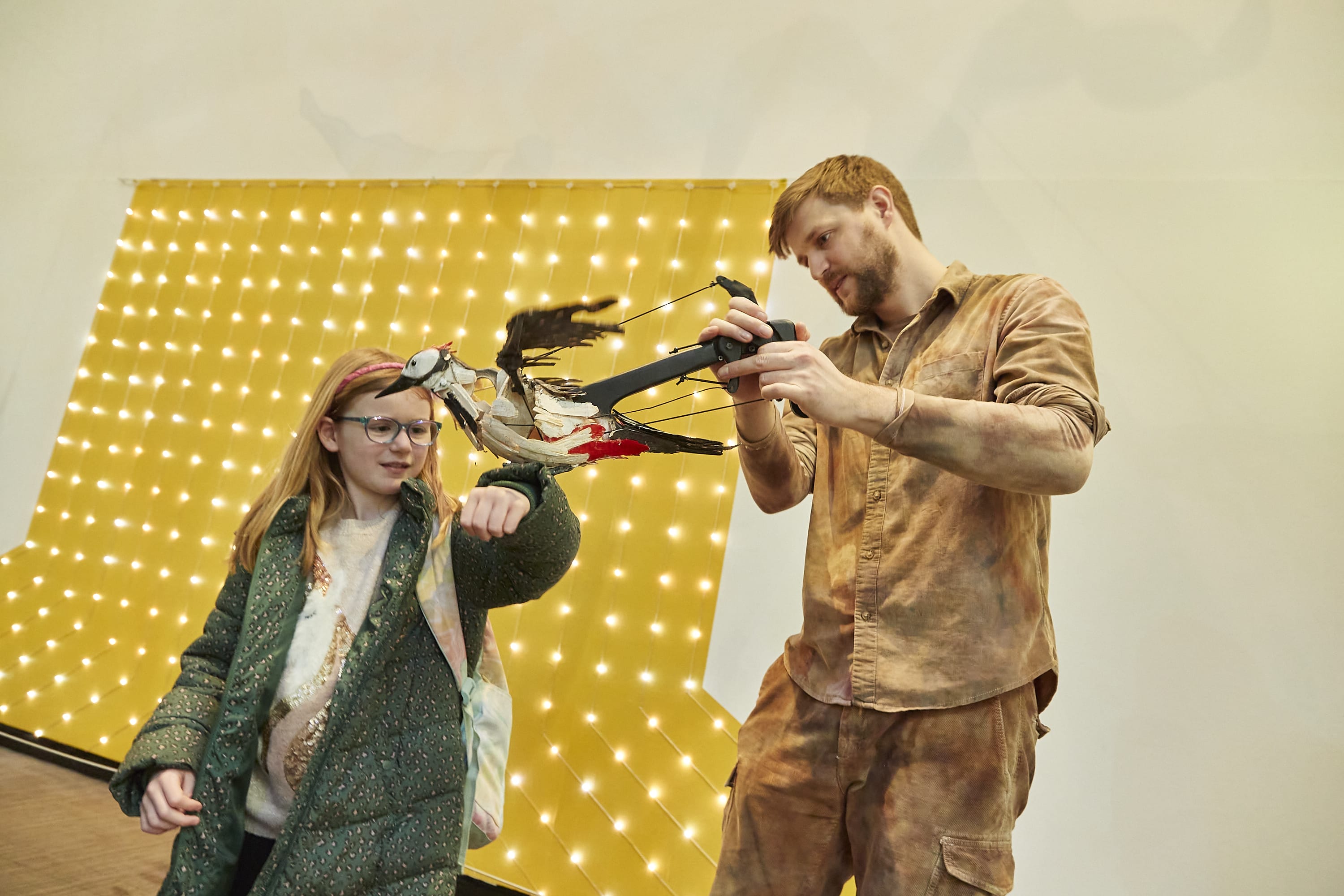 A Puppeteer introduces a bird puppet to a small girl.