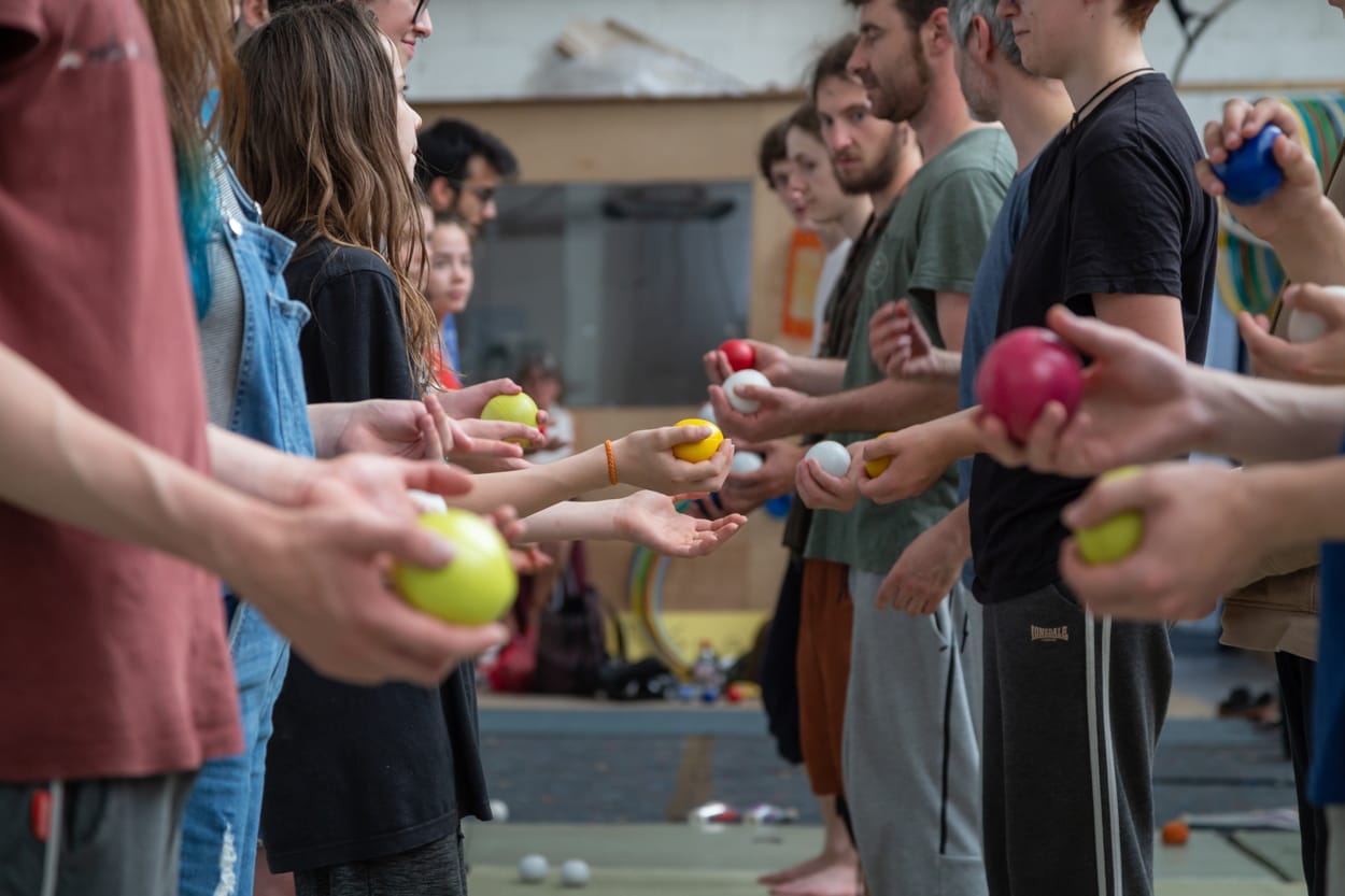 A photo of two rows of hands, holding juggling balls, taking part in a workshop.