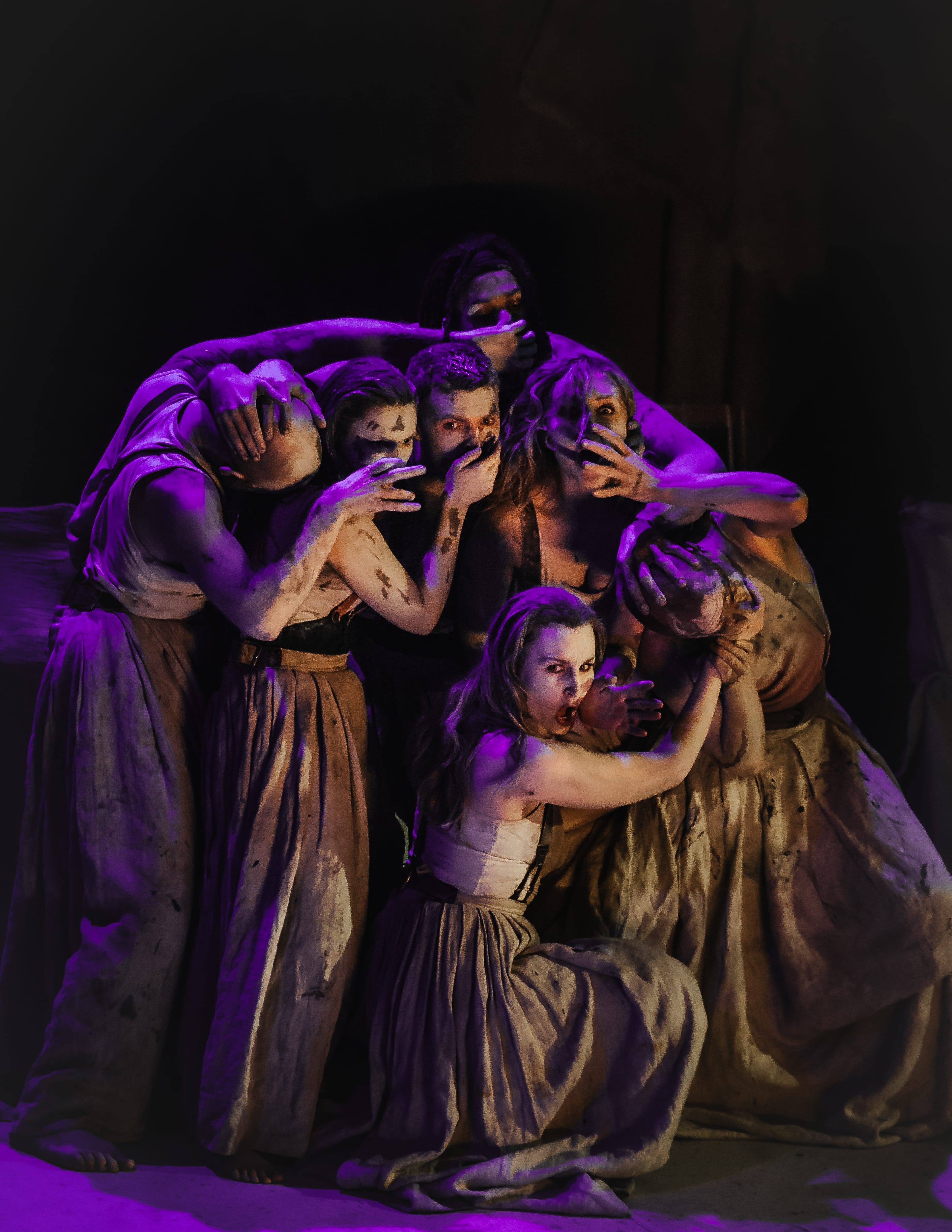 A group of performers, on stage are draped over one another.