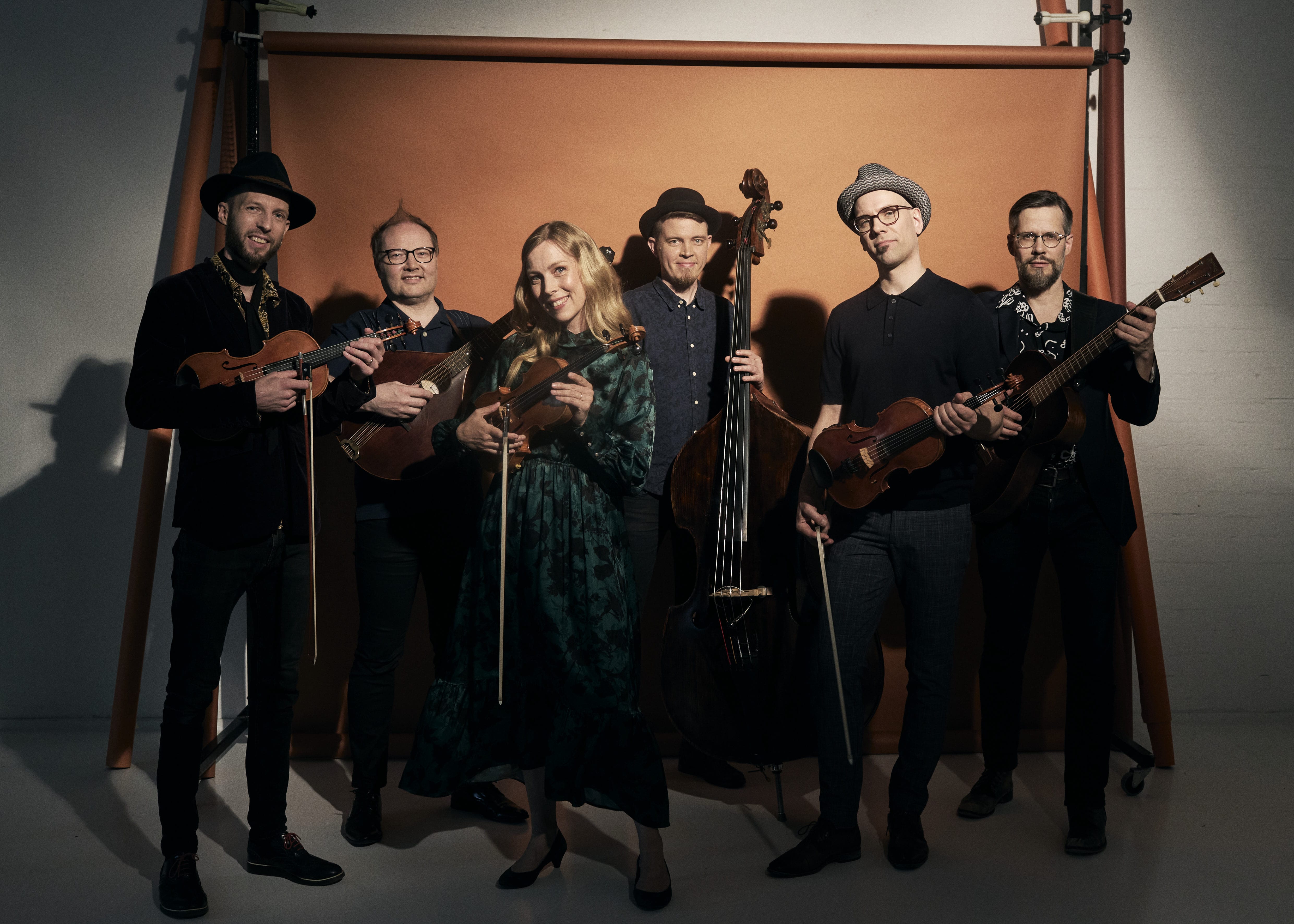 The band is dramatically photographed against an orange backdrop holding their instruments.