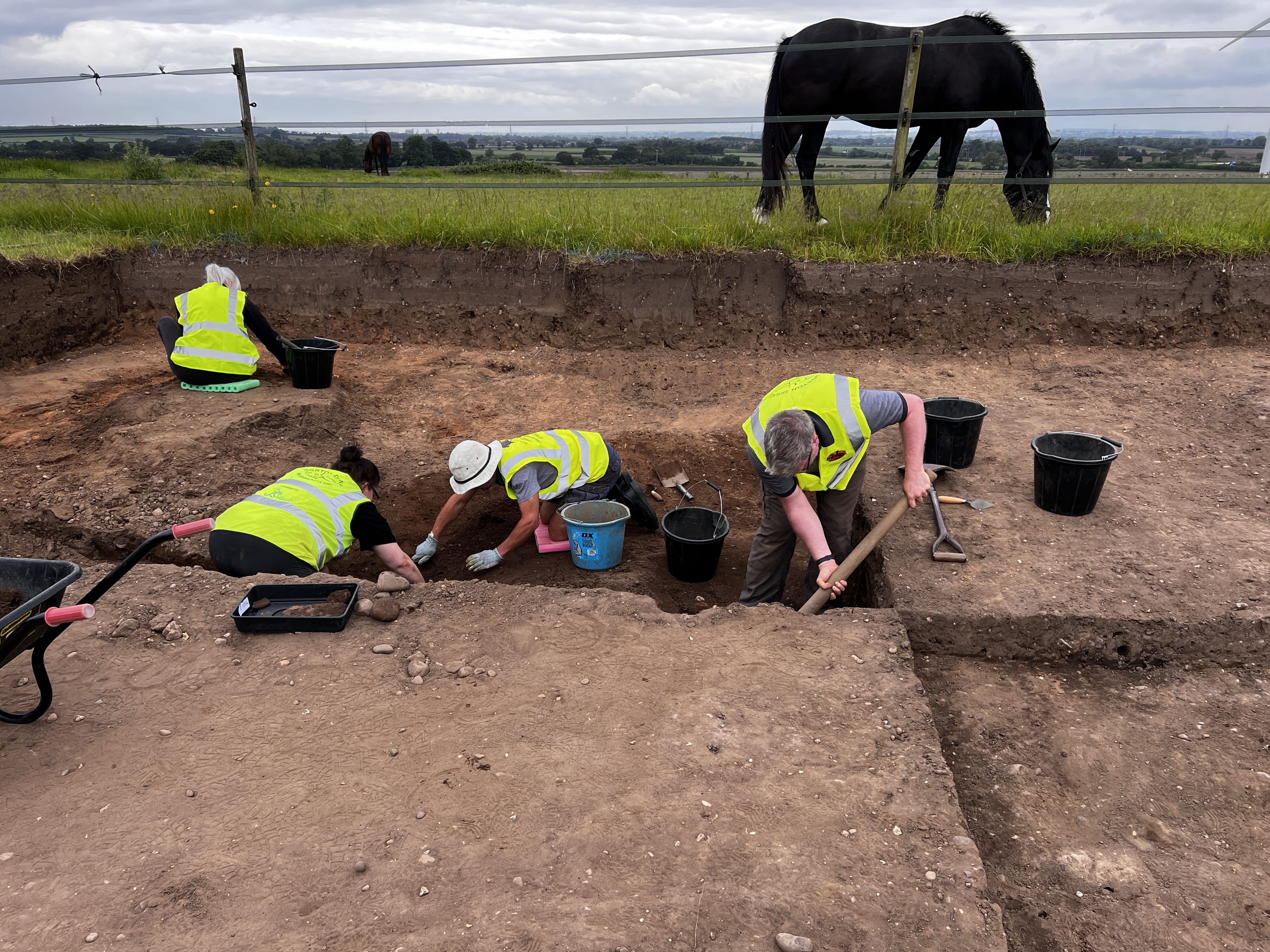 A group of people take part in an archaeological dig.