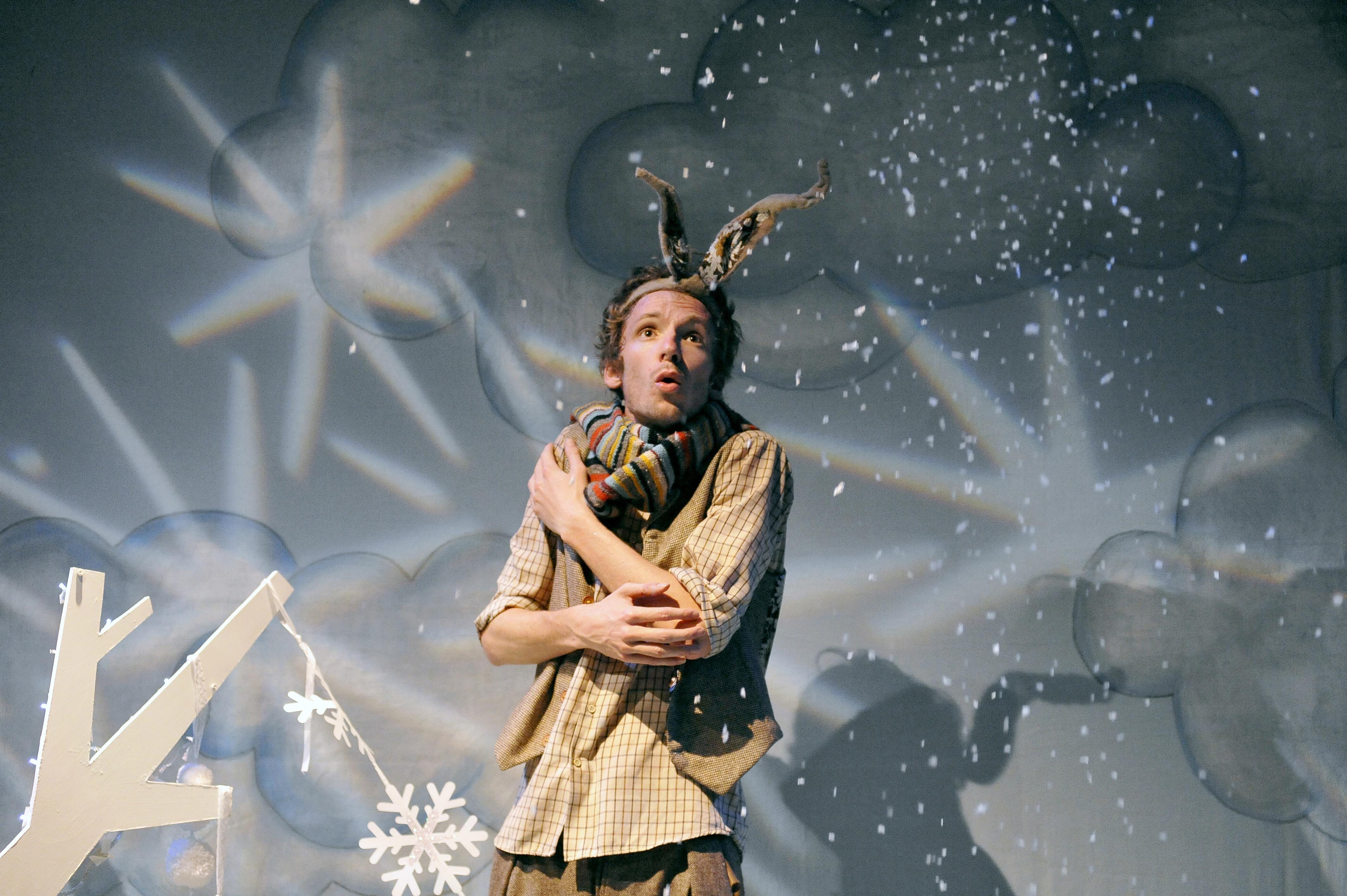 an actor dressed as a hare embraces himself on a snowy stage