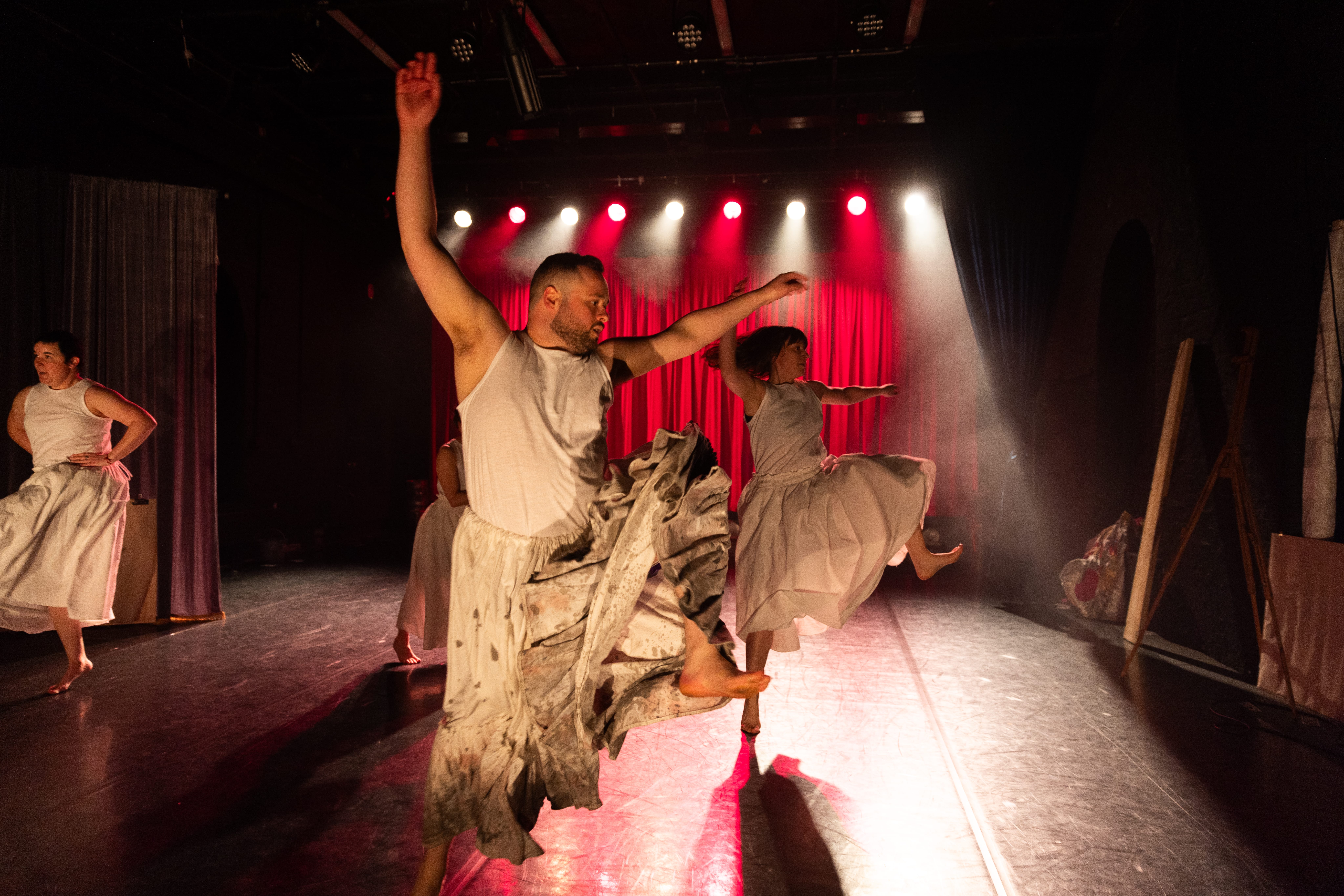 A group of people dressed in white wearing big skirts are dancing on a stage