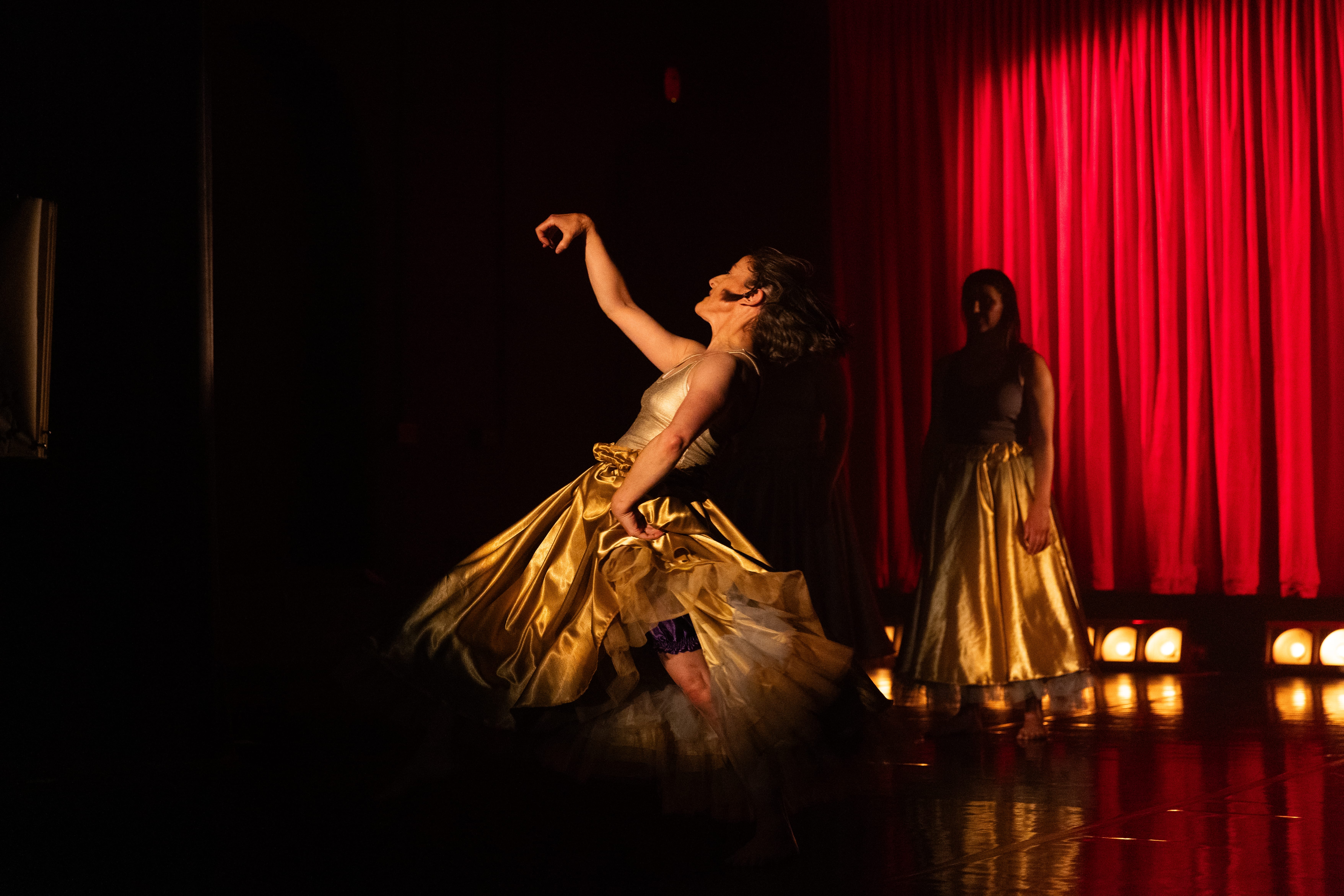 A woman wearing a golden dress performs on stage