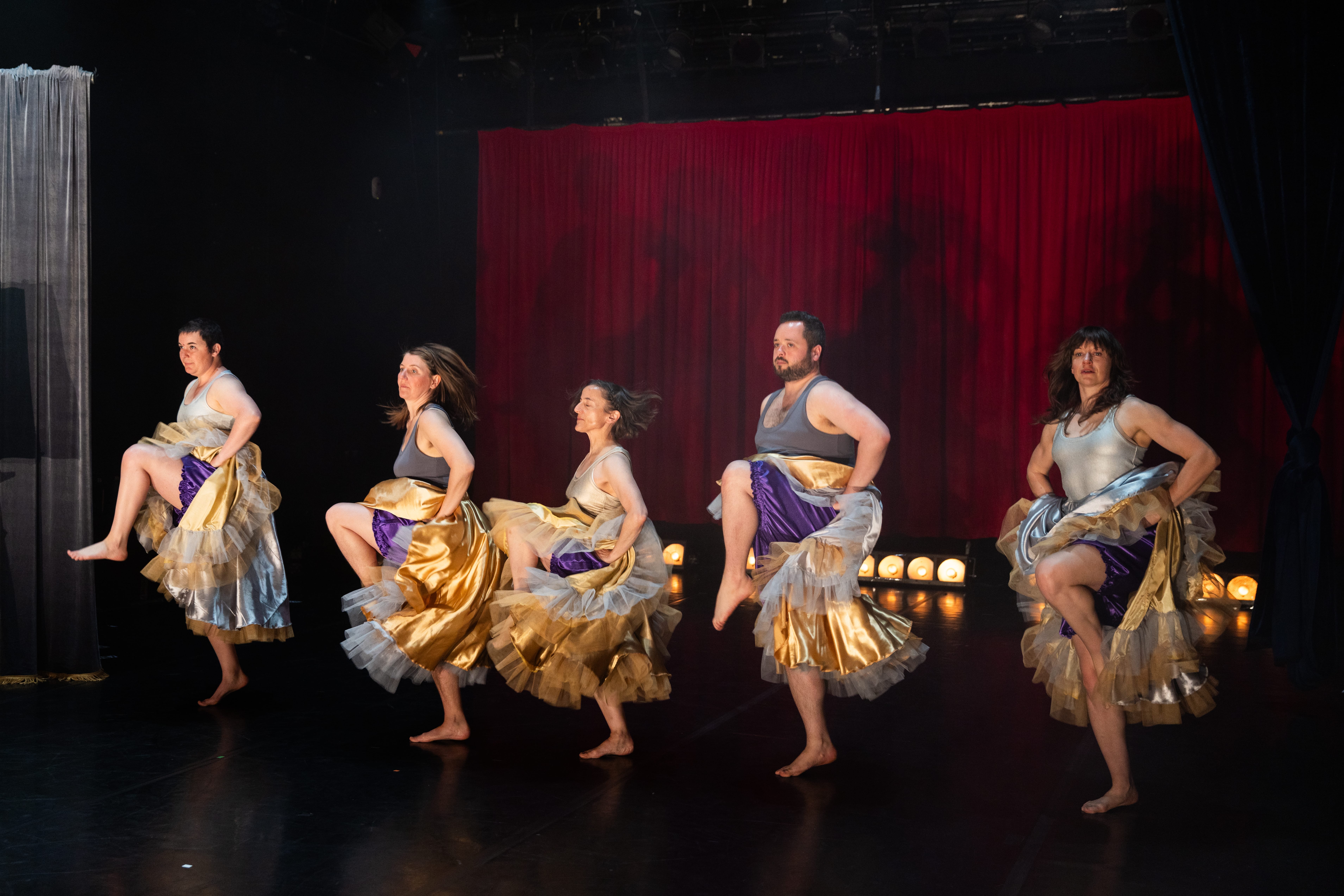 A group of people in golden skirts are dancing the can-can