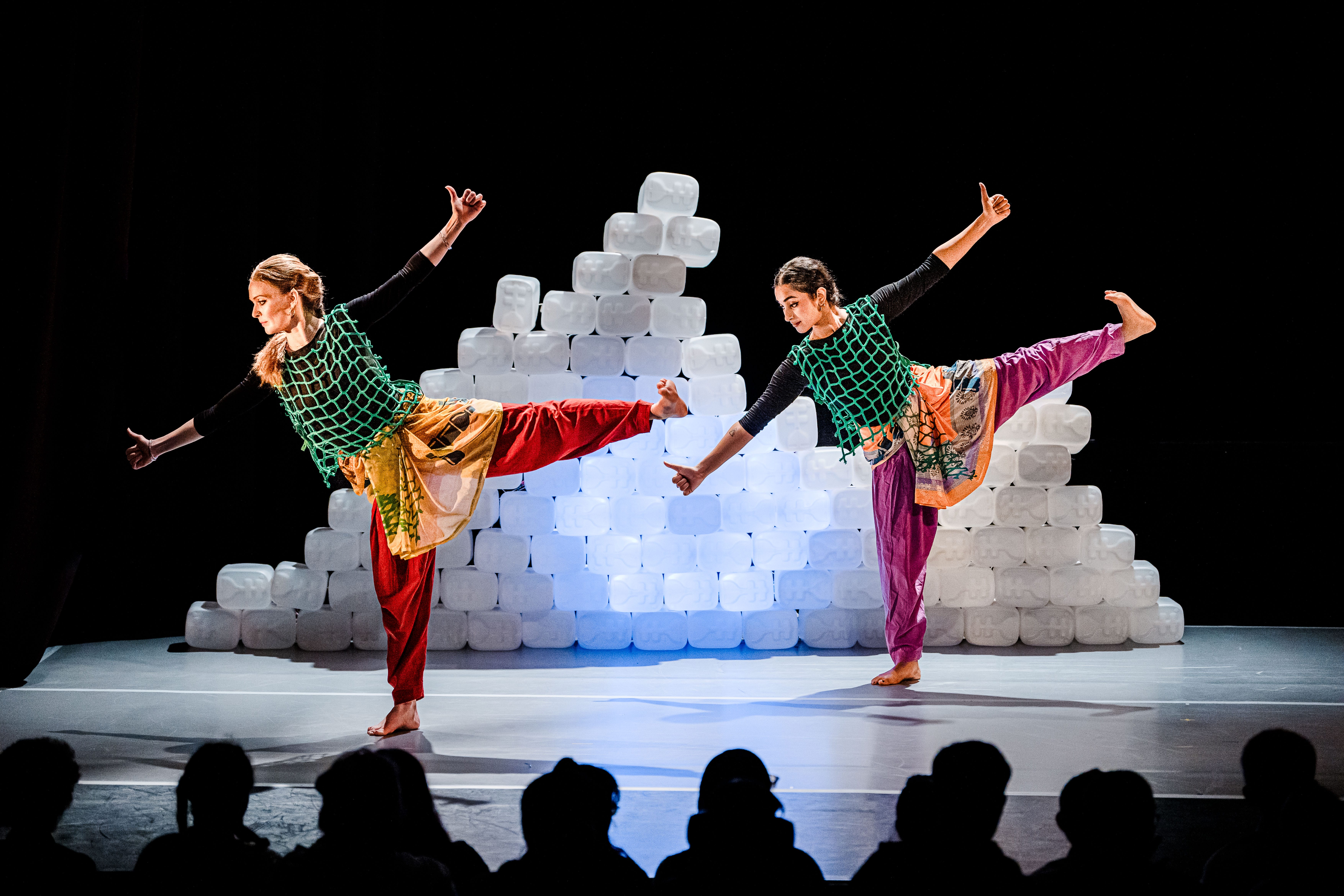 Two women are dancing in front of a white plastic wall