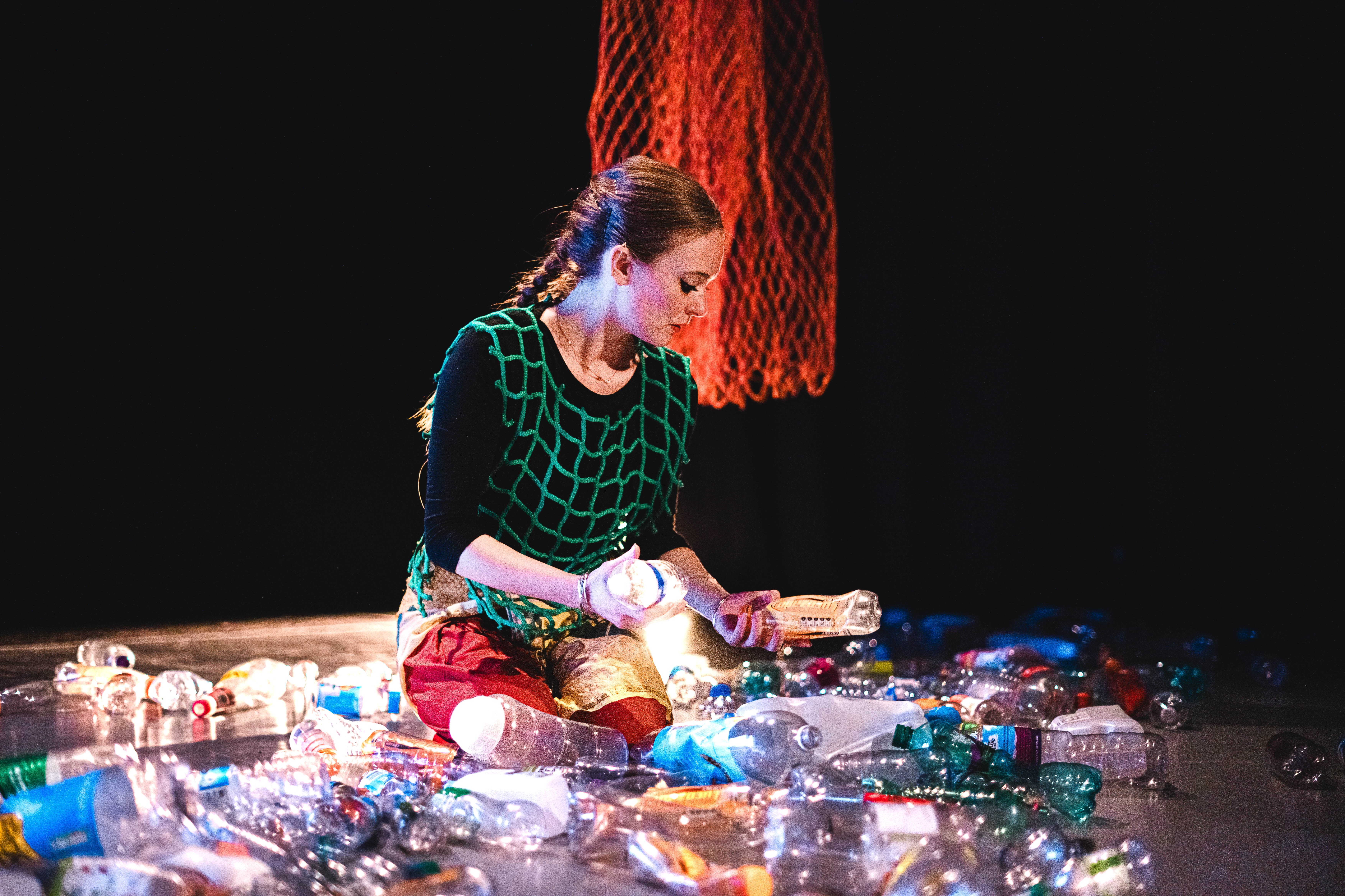 A woman is sitting in the middle of a pile of plastic bottles