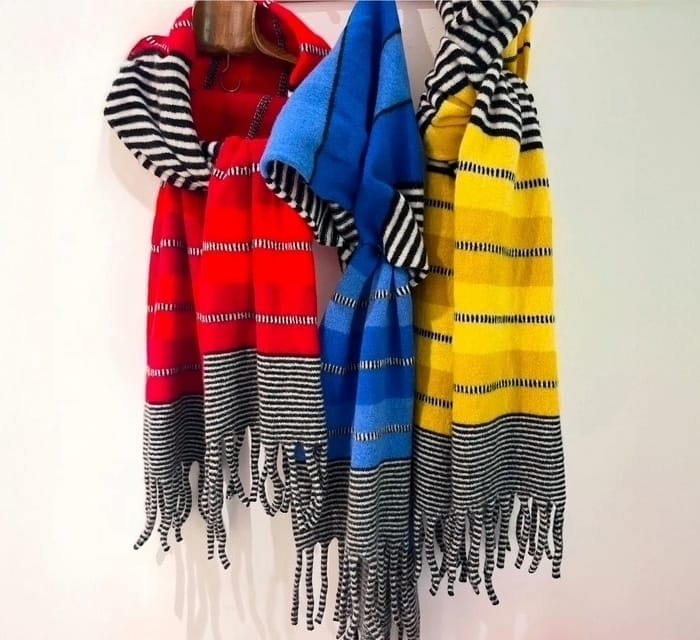 An image depicting three brightly coloured striped scarves. They are red, blue and yellow, all striped with black and white.