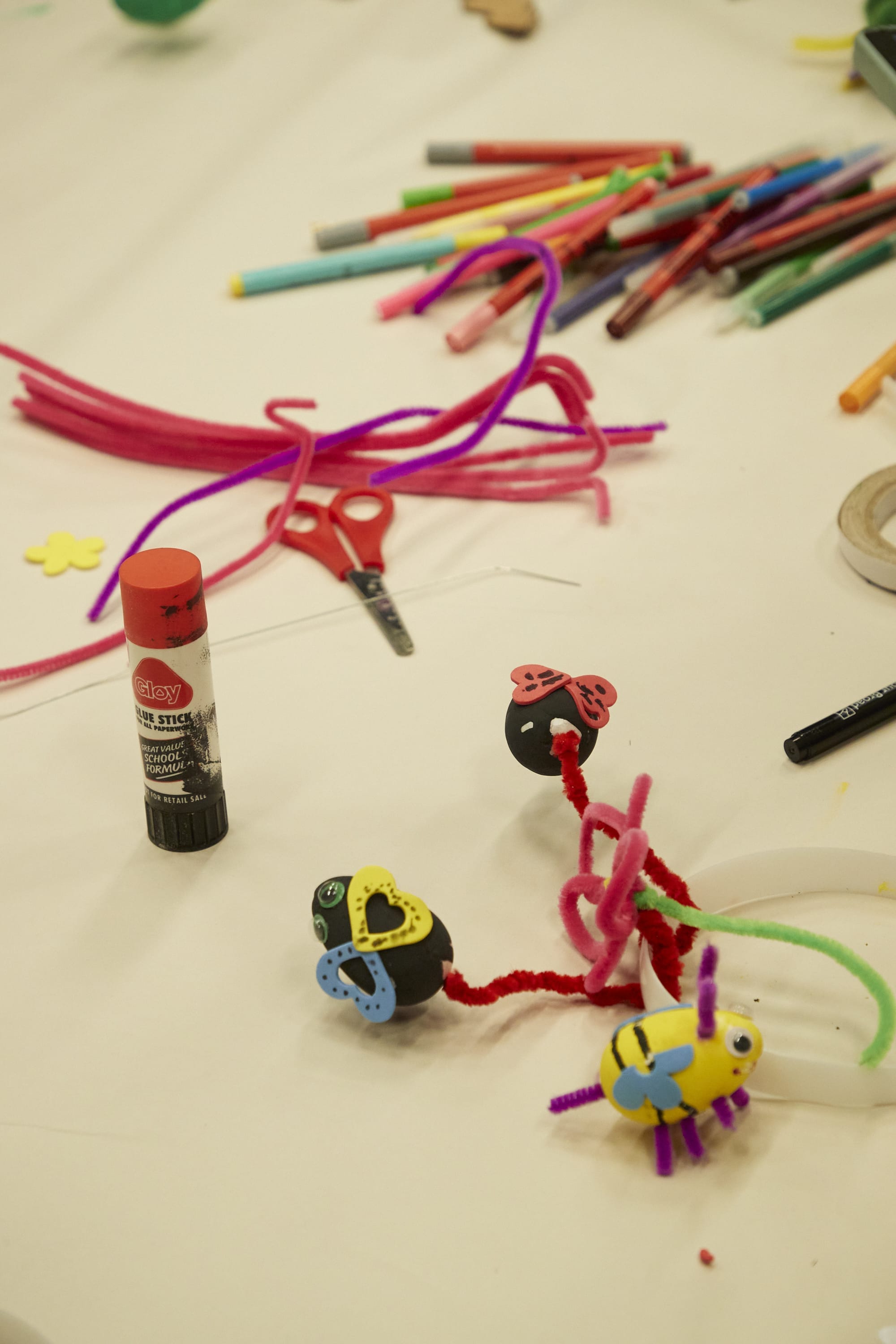 Little creatures made from pipe cleaners are surrounded by craft supplies