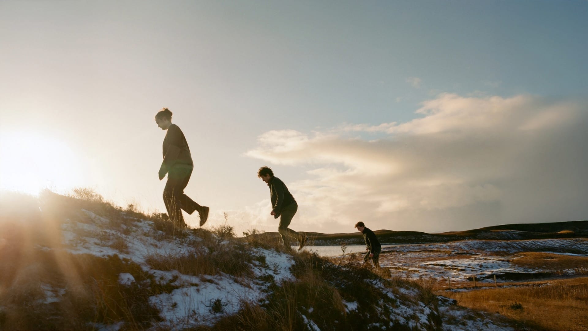 The trio are trekking up a snow covered hill while dawn breaks