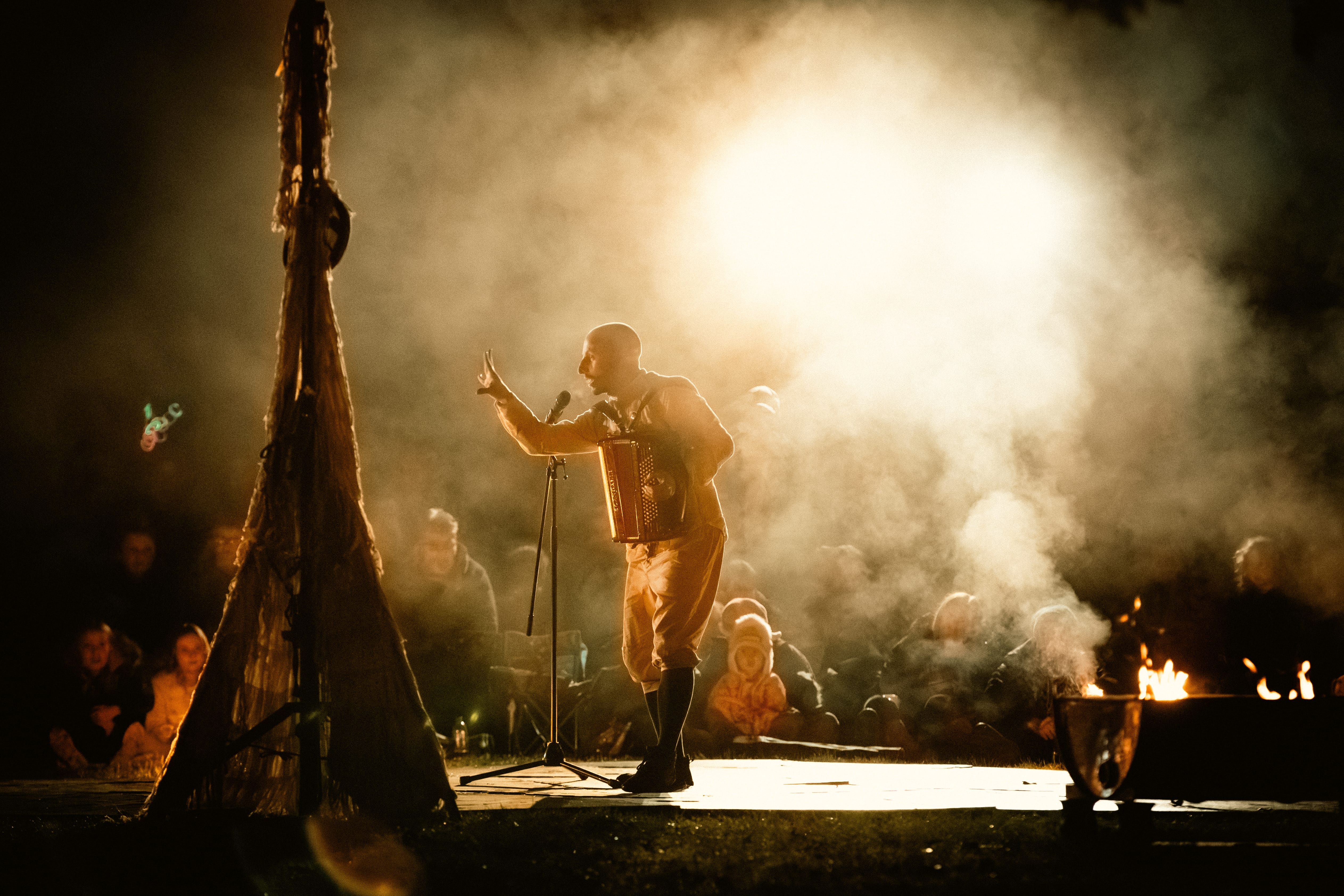 A silhouette of an actor talking into a microphone with smoke around him