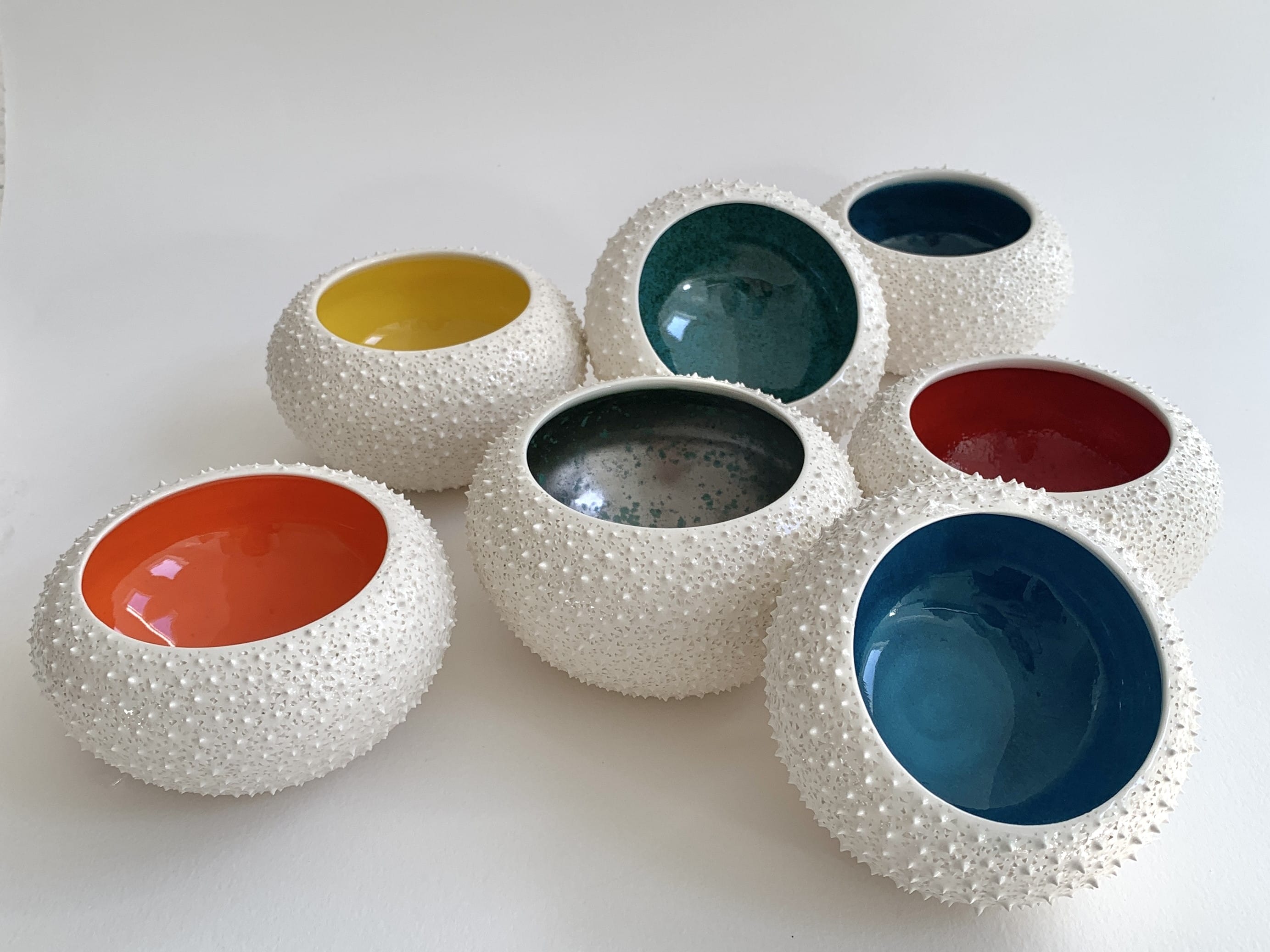 Bowls with a white, textural, dotted exterior and a glazed smooth, vibrantly coloured interior