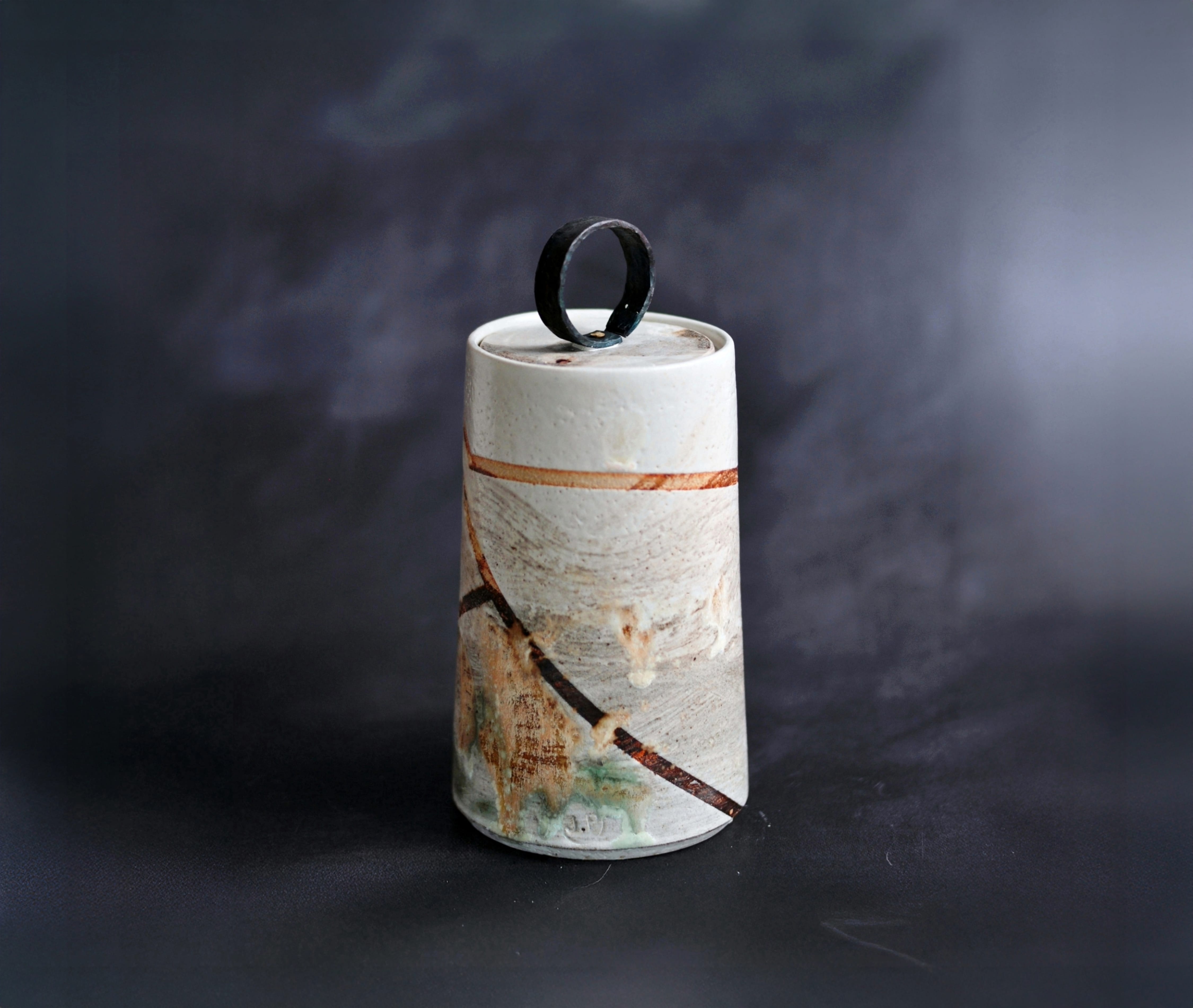 Ivory item with gold and copper detailing in lines going across.