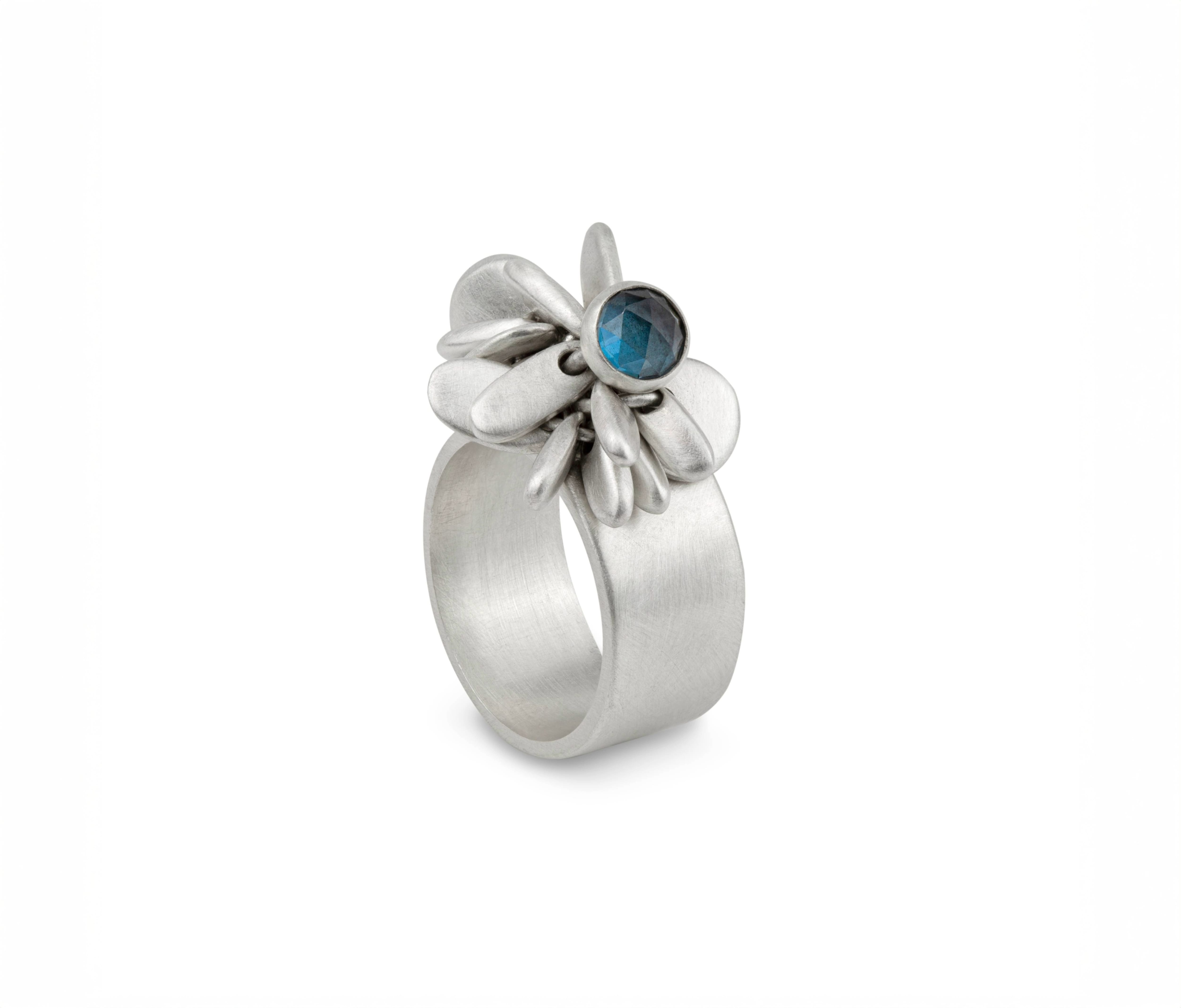Silver ring with a flower like design and a dark blue gemstone in the centre.