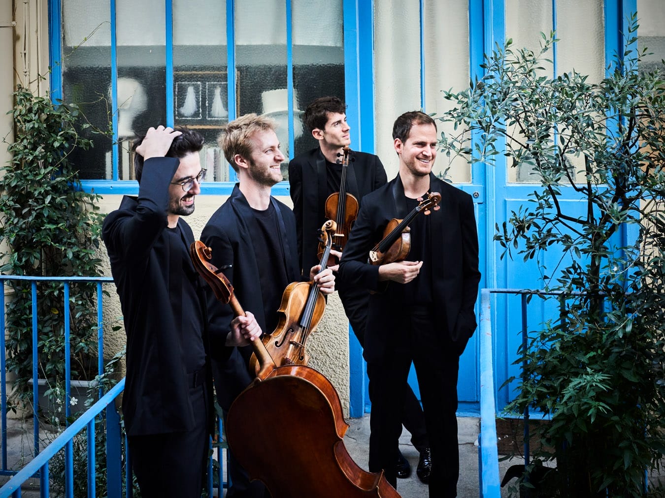 The photo is a candid shot of the musicians smiling with their instruments