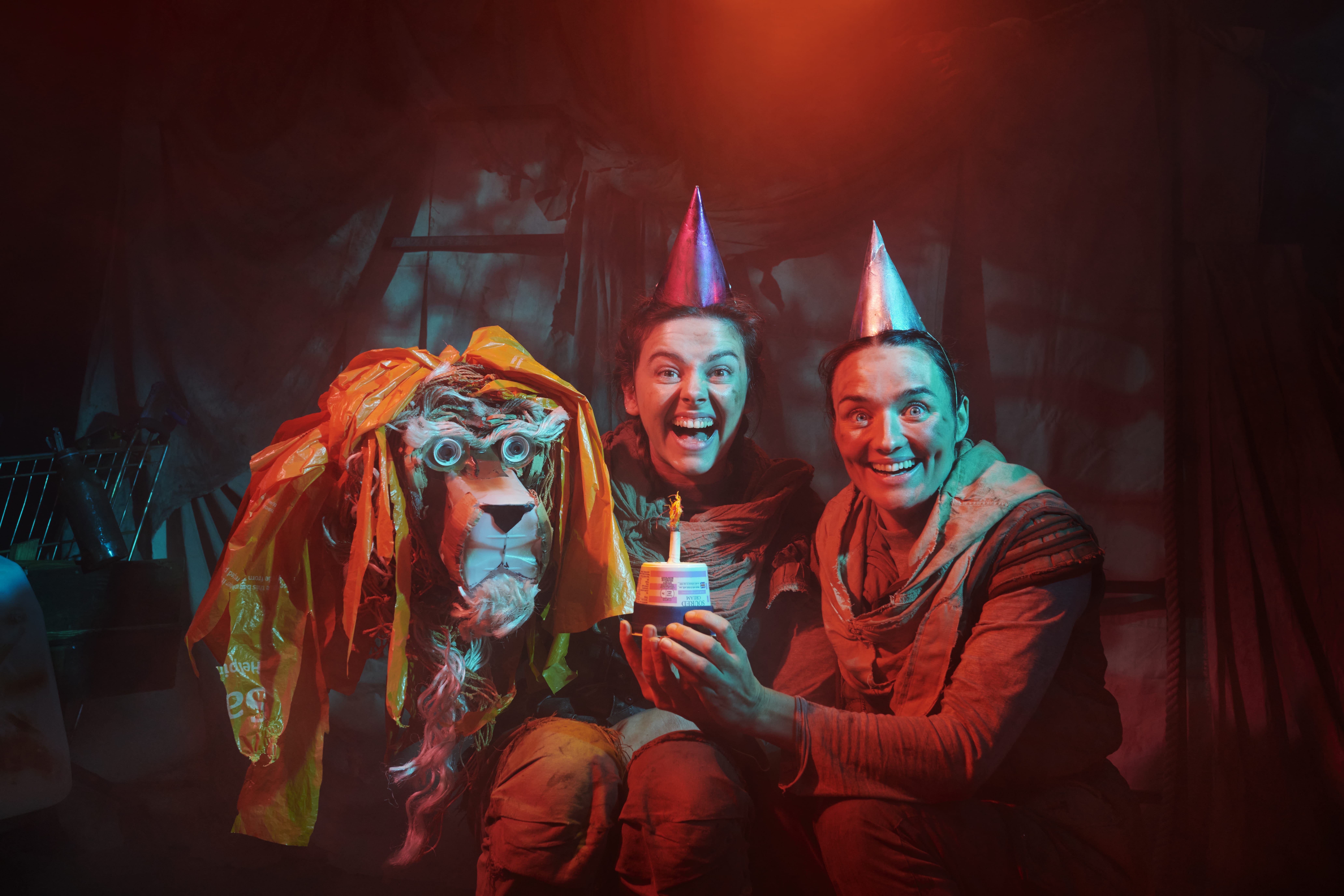 Teo actors and a lion head made of scrap smile for a birthday photo
