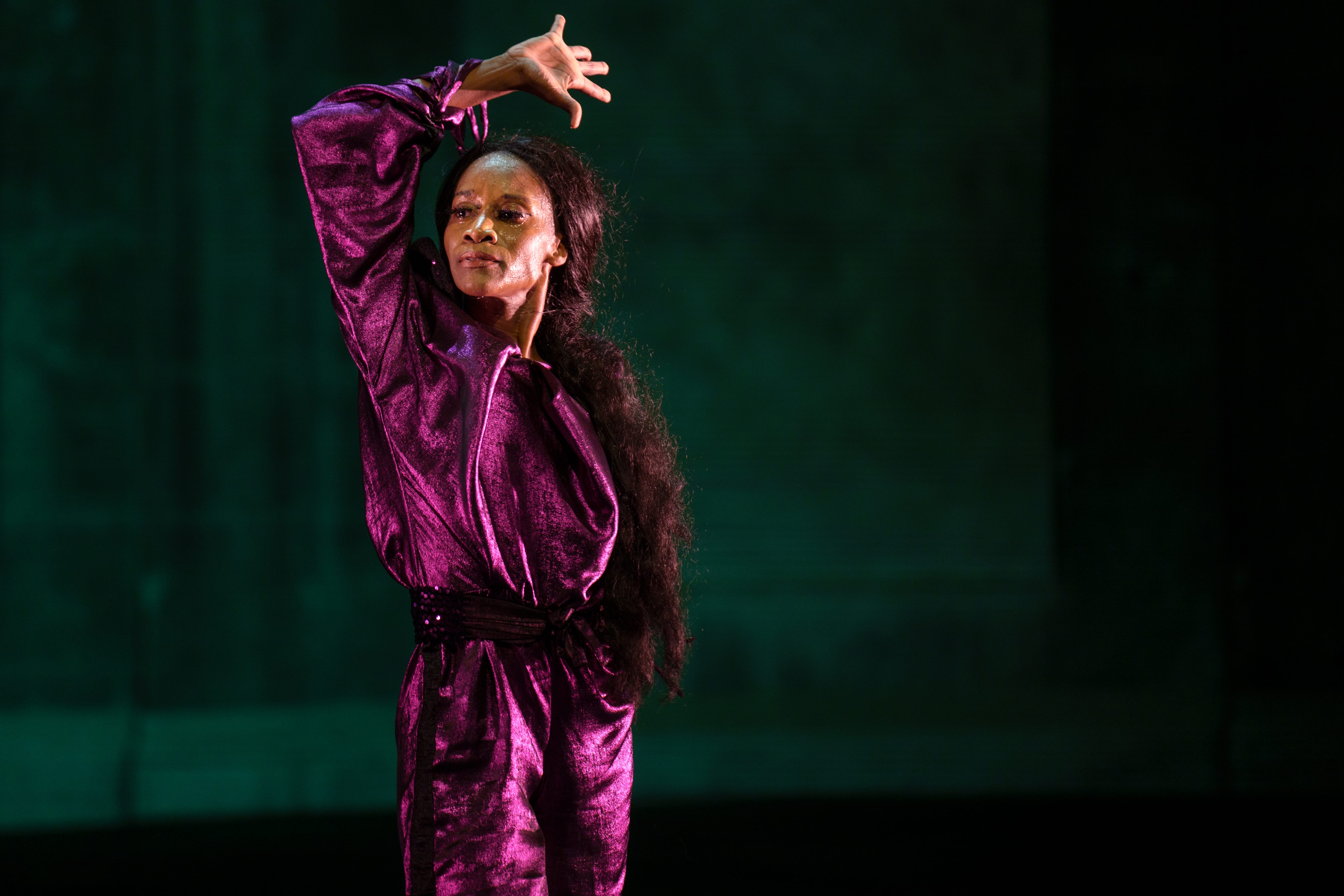 A woman dressed in purple dances flamenco on stage