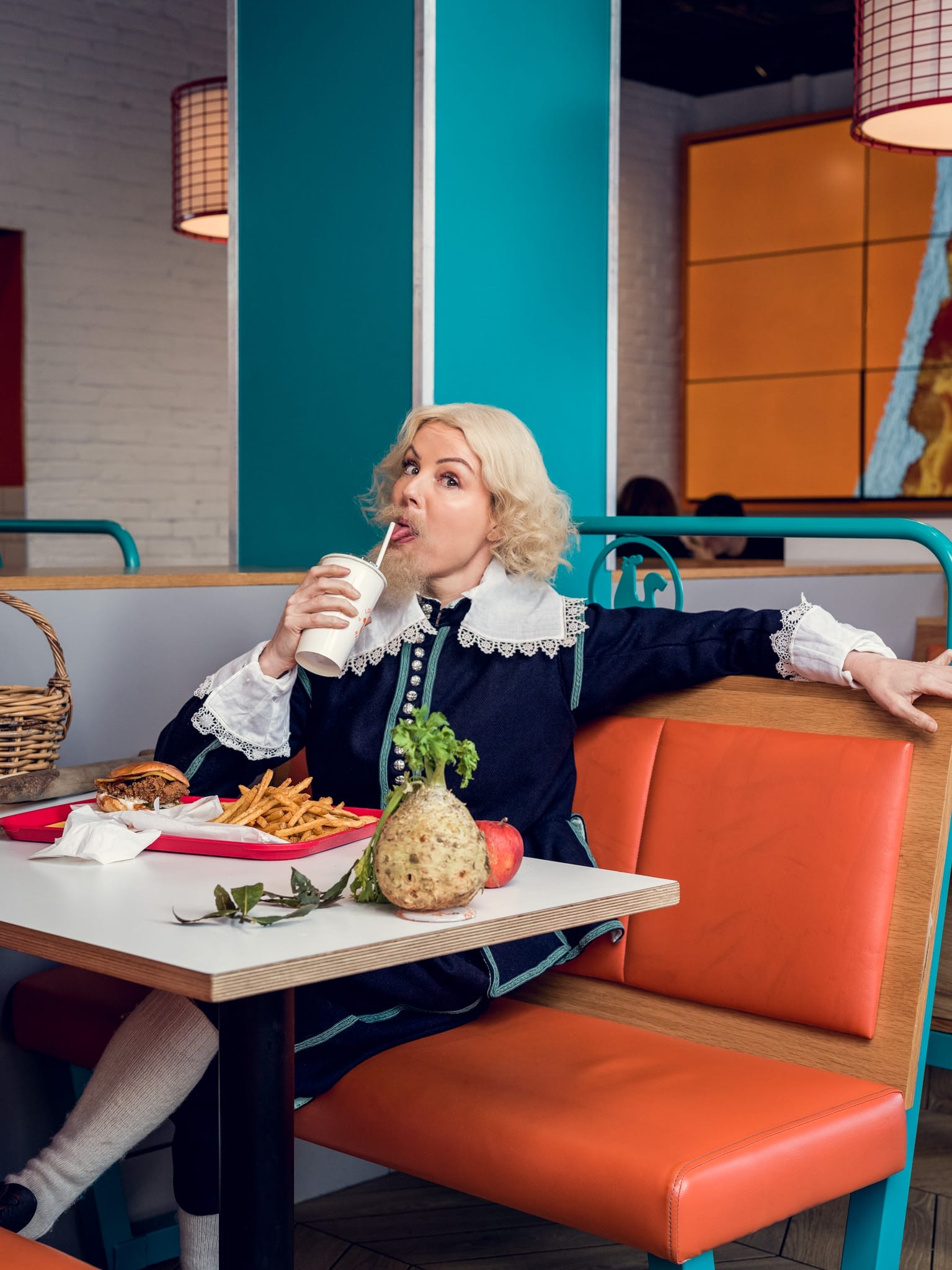Victoria Melody is sat in a fast food restaurant, in historical costume.