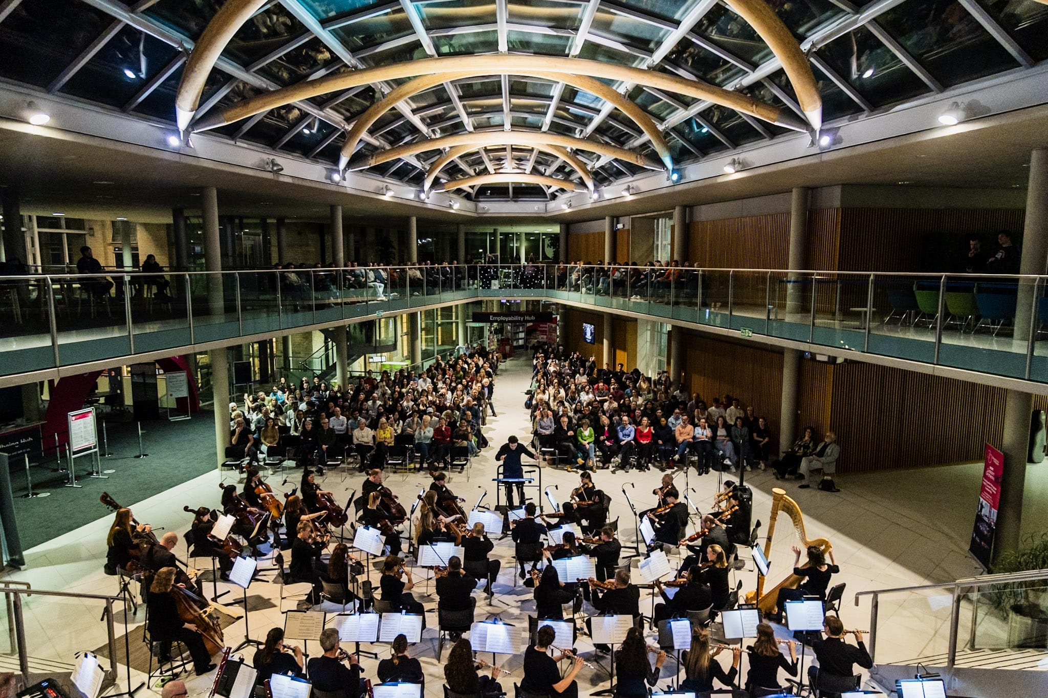 a wide shot of a concert with an orchestra and the audience visible