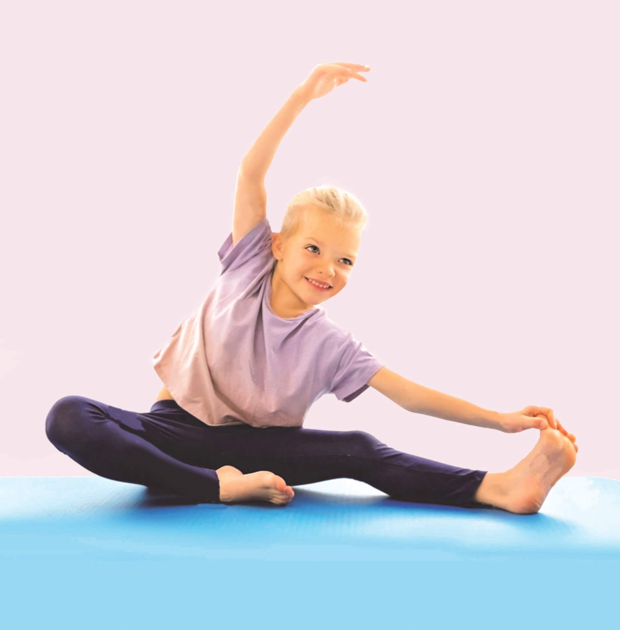 A child wearing leggings and a lilac t-shirt sits on the floor and stretches.
