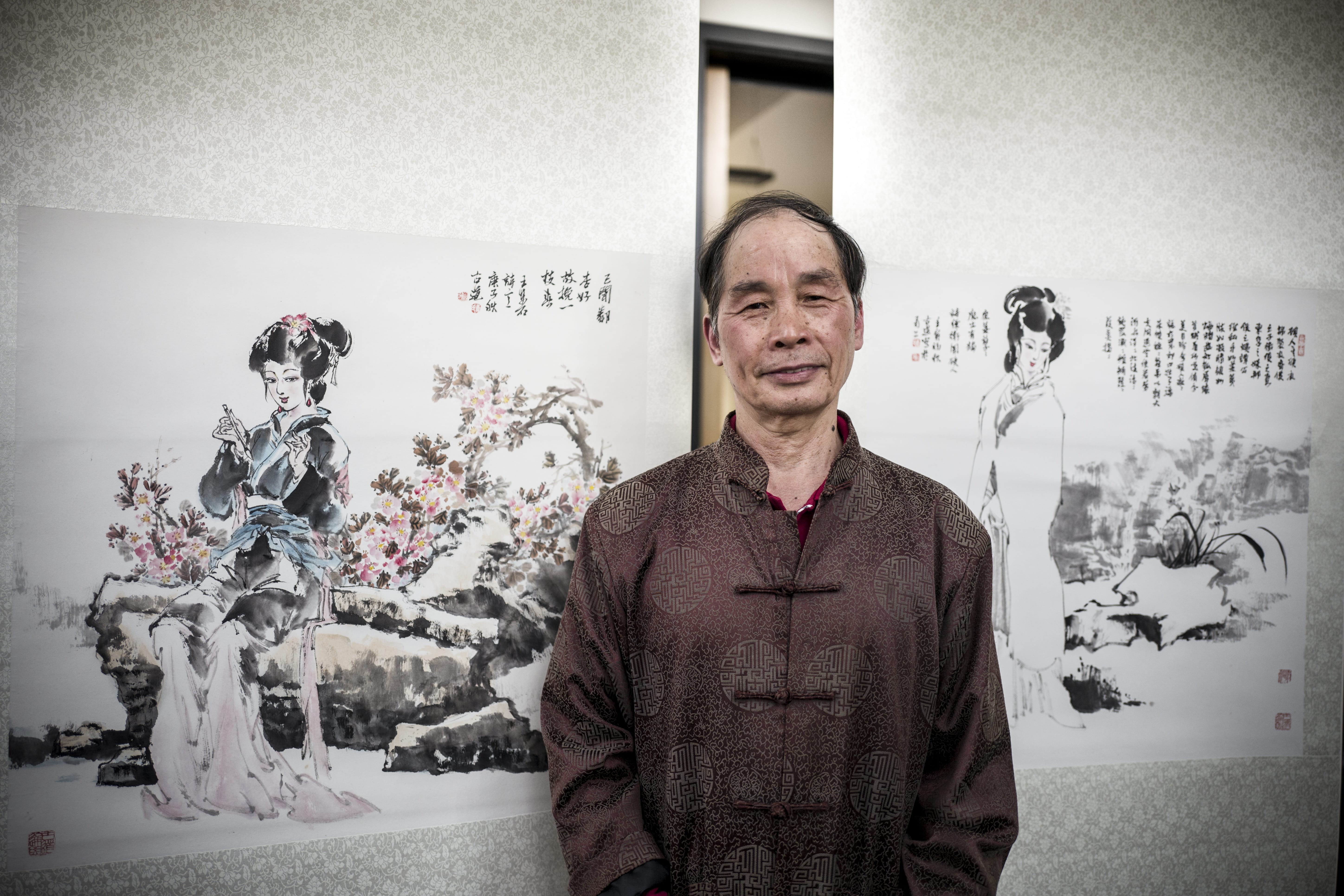 Artist Li Qingyu stands in front of his traditional Chinese paintings