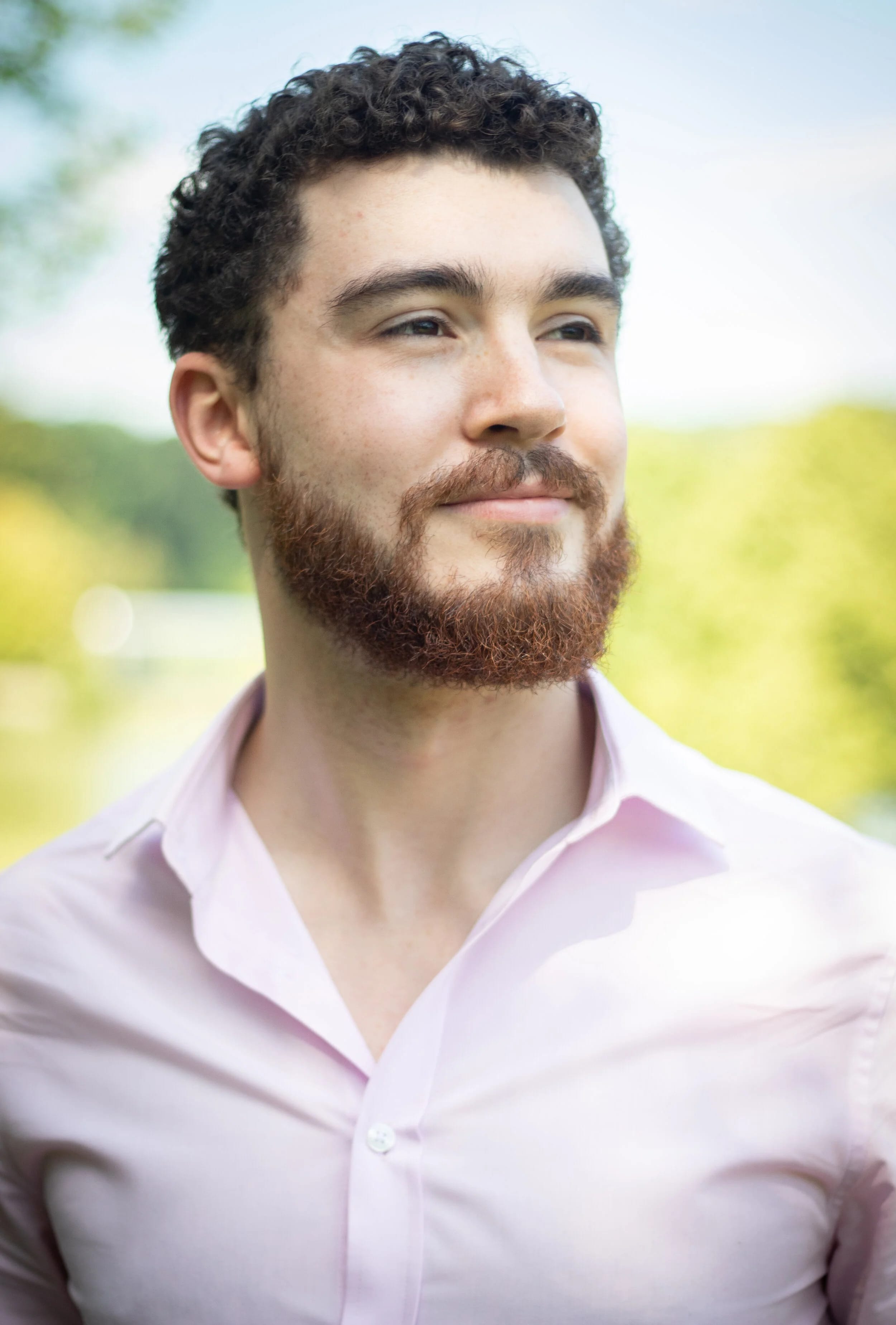 A man looks to the distance, wearing a pink shirt.