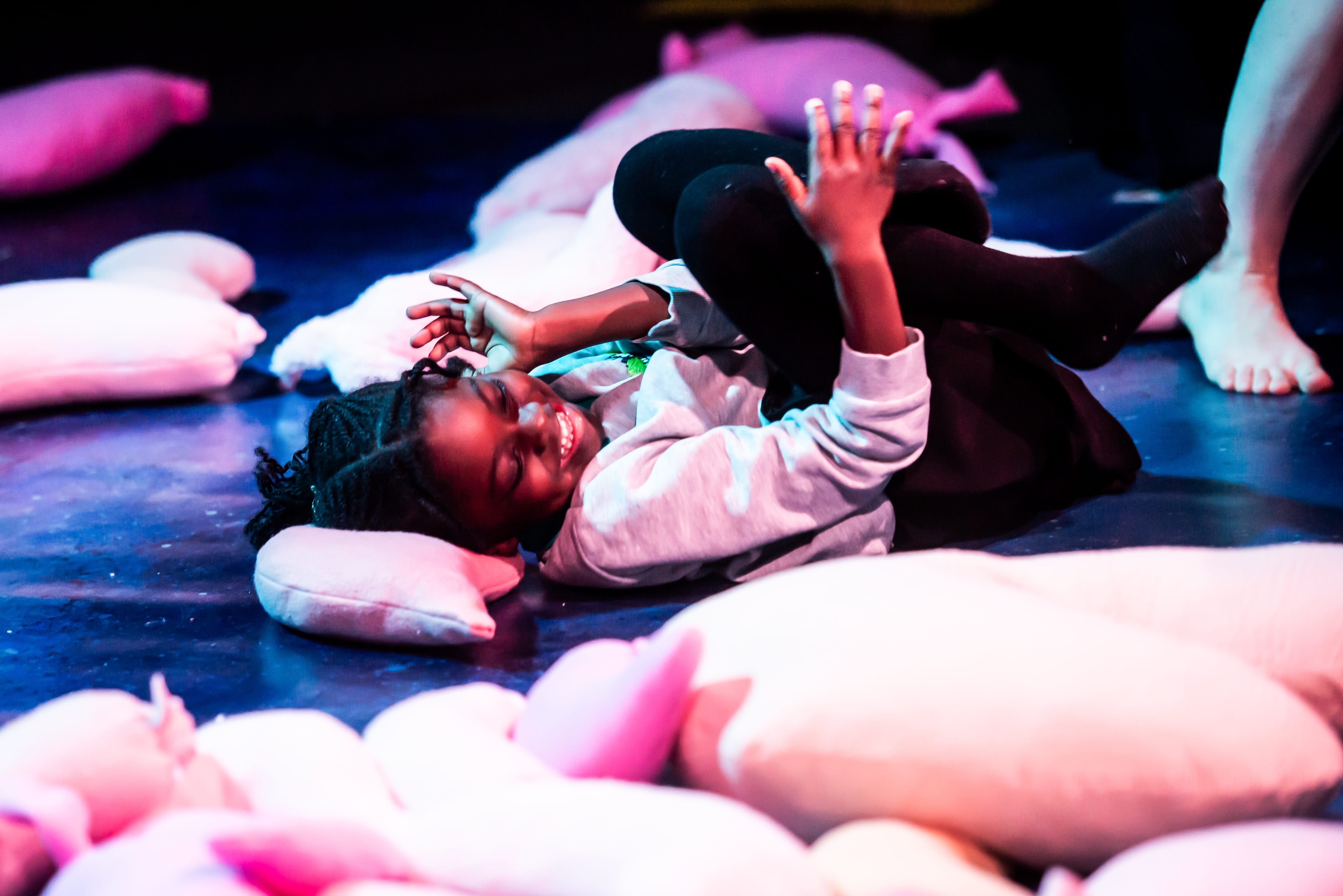 A young girl giggles as she lies on the floor.