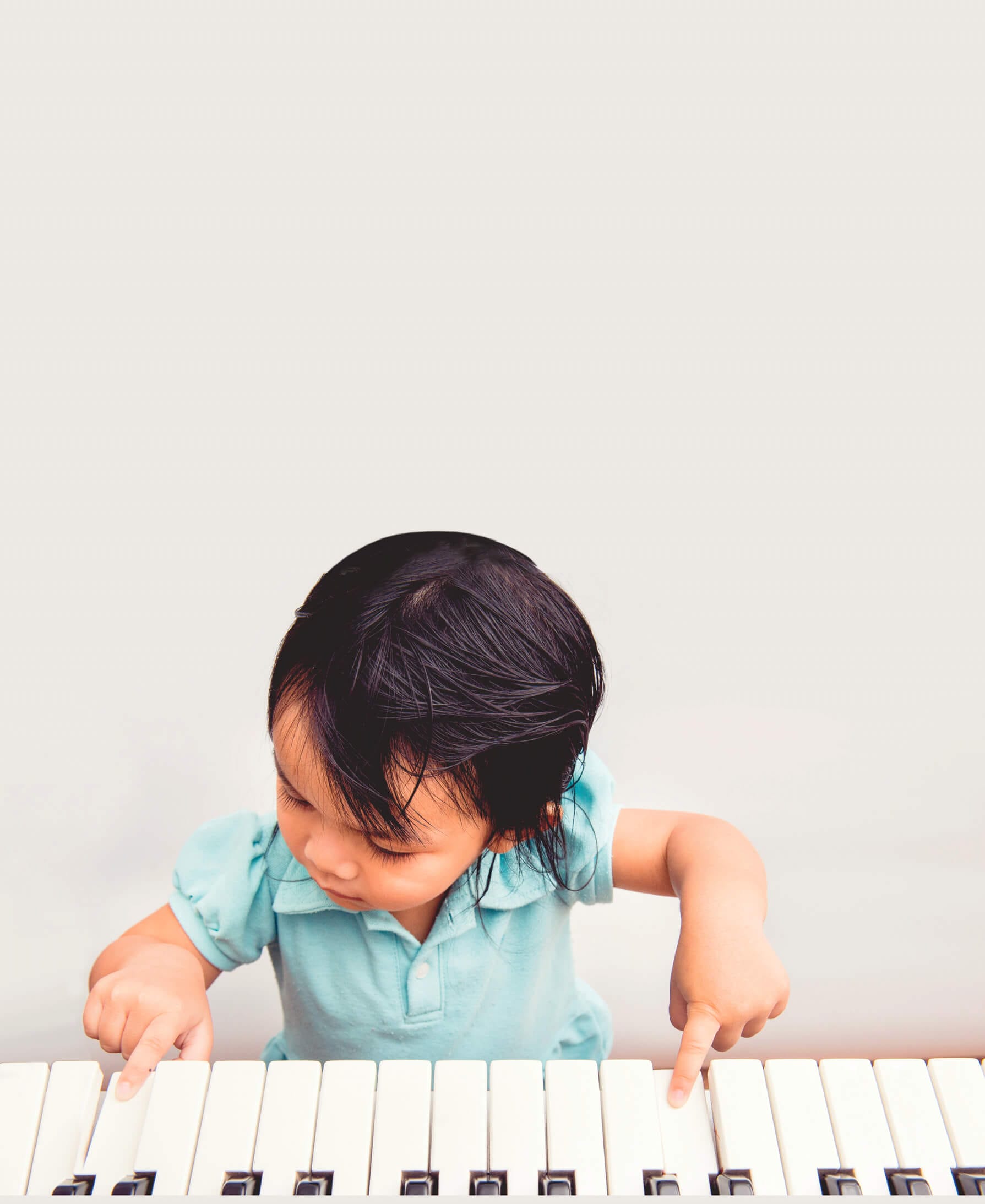 A small child sits and plays a keyboard.