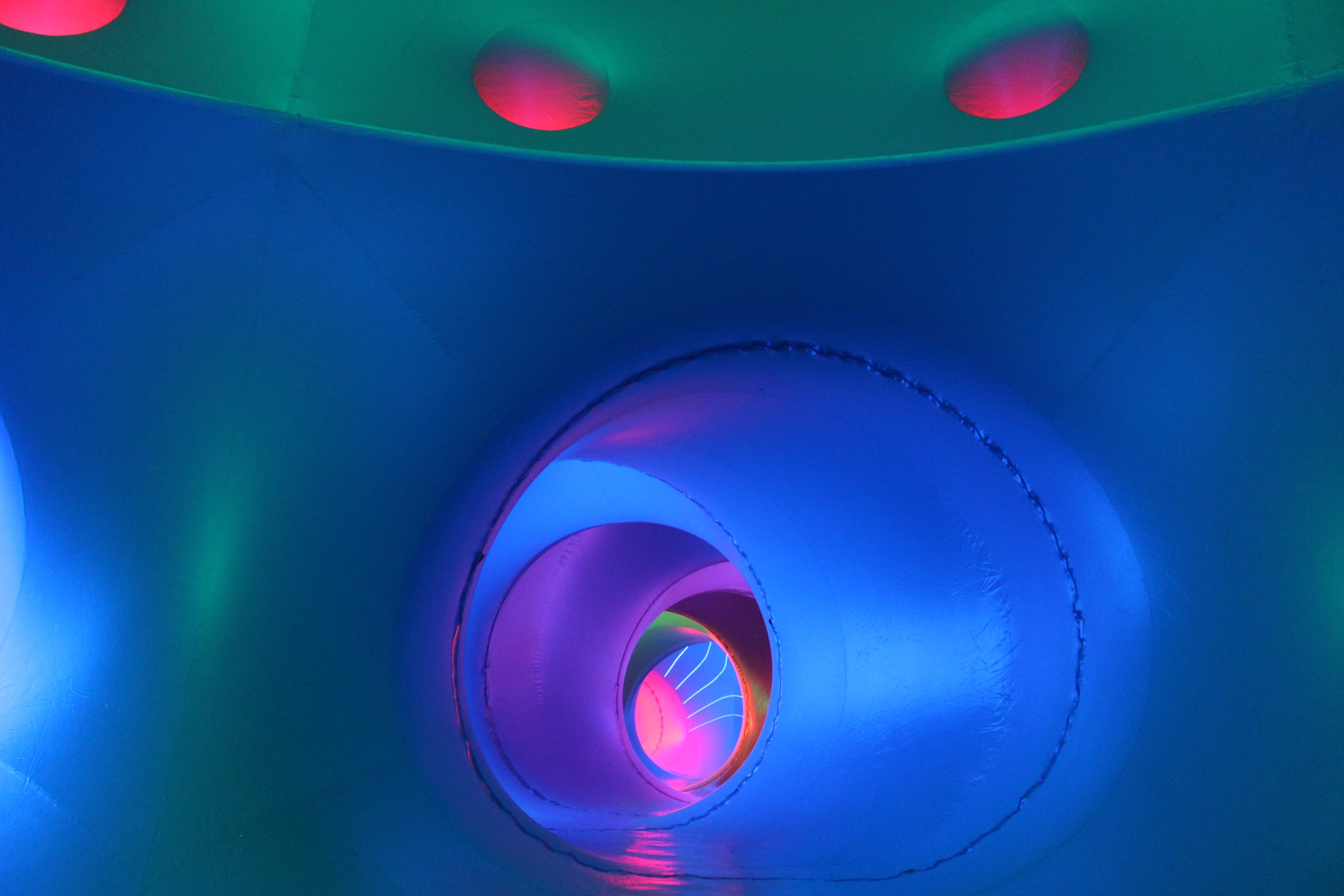 A photograph from inside a tunnelled structure bathed in multi-coloured light.