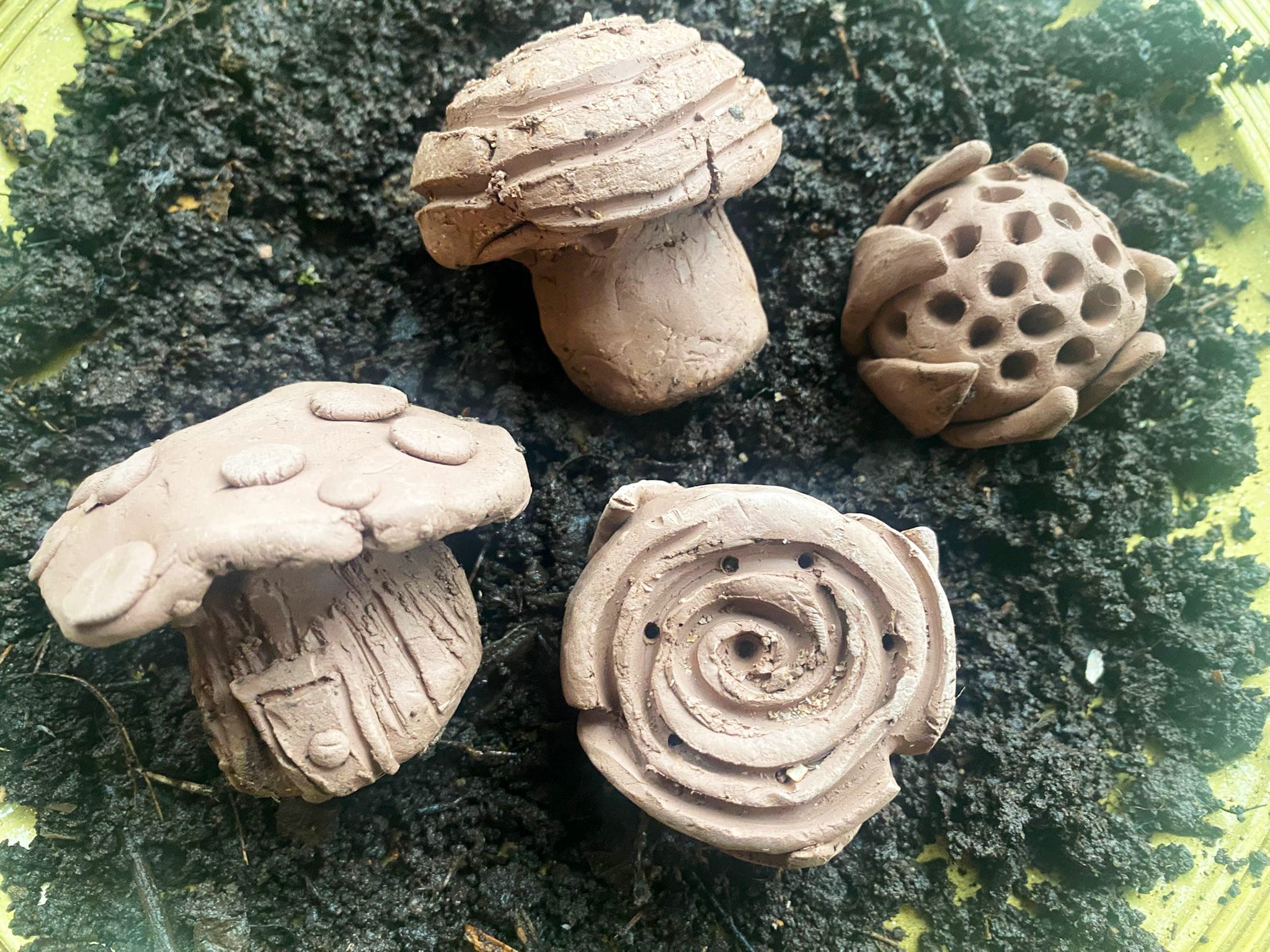 Small clay sculptures sit on grass