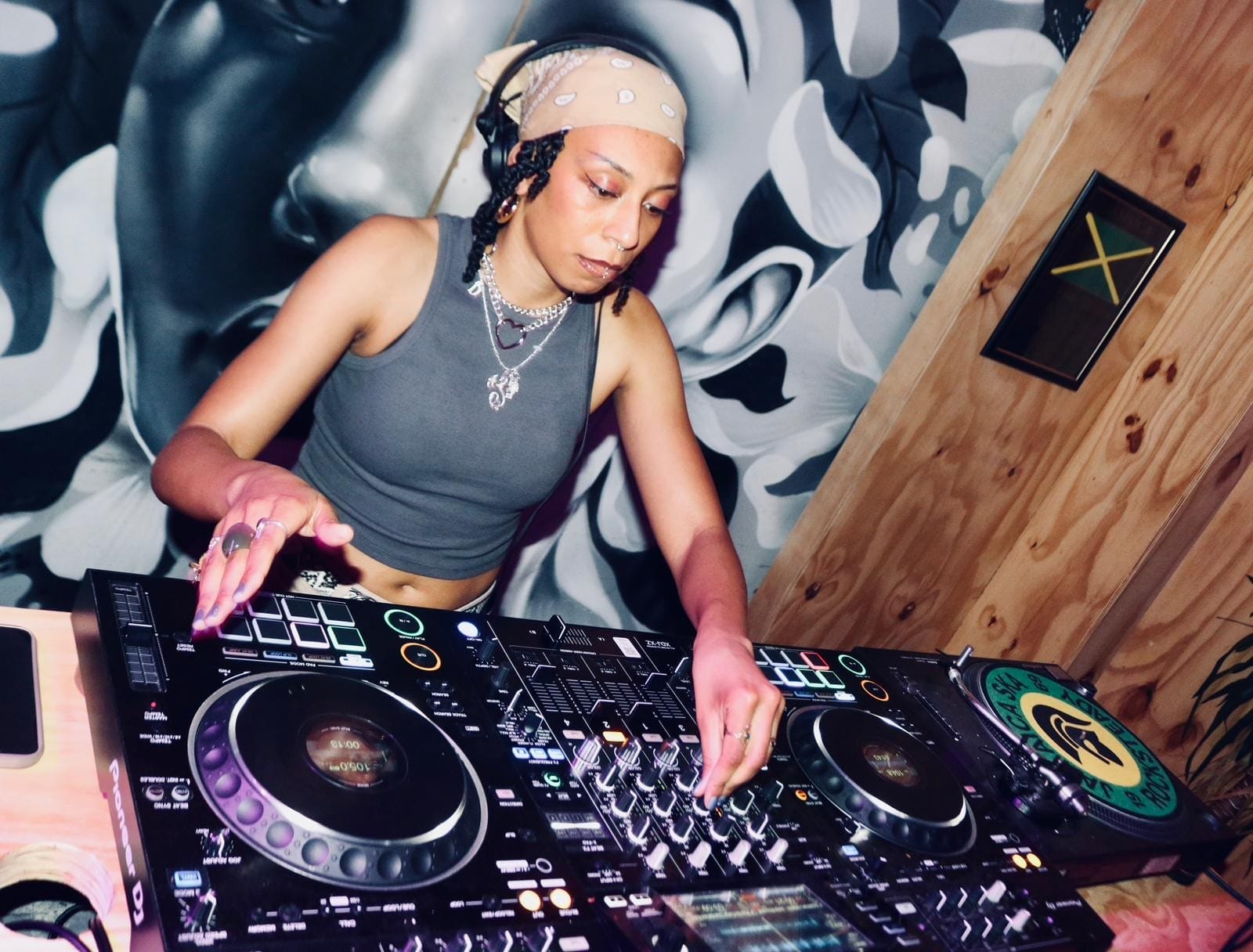 DJ and producer Rewyld wearing headphones and performing on DJ decks